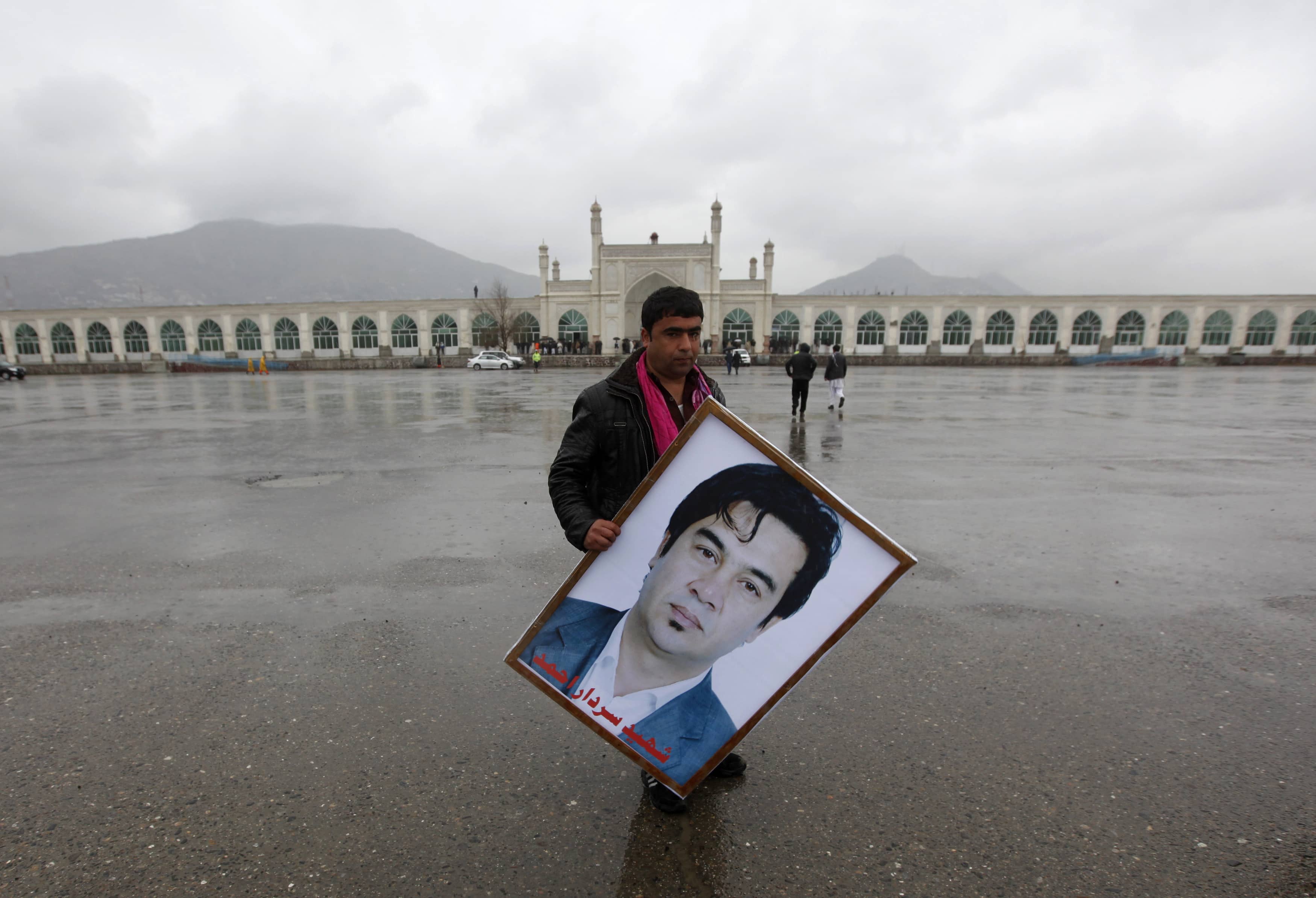 An Afghan man holds a picture of journalist Sardar Ahmad of Agence France-Presse, during his funeral ceremony in Kabul, 23 March 2014, REUTERS/Mohammad Ismail