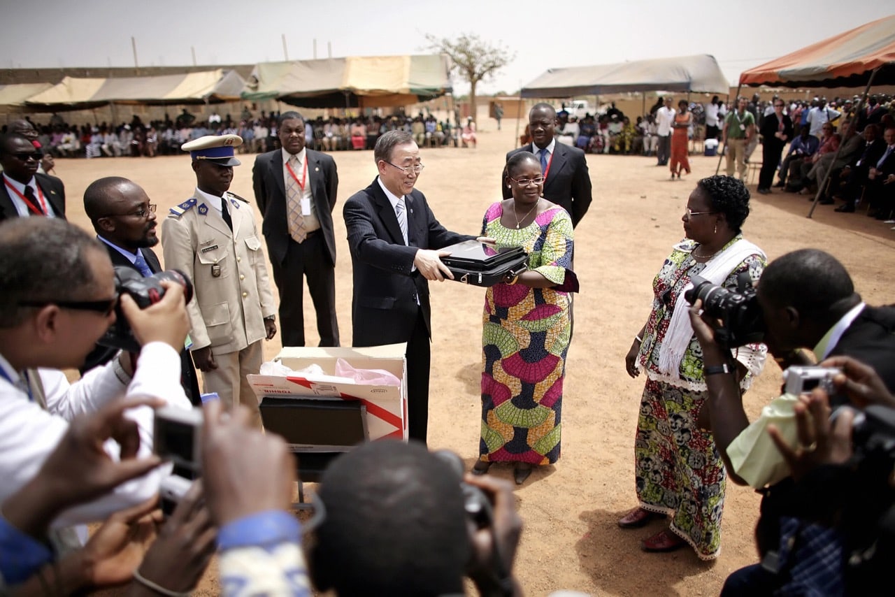 United Nations Secretary-General Ban Ki-moon (CL) presents Burkina Faso's Minister of Basic Education and Literacy with a new laptop during a visit to Manegda Primary School in Burkina Faso, 23 April 2008, Leon Neal/AFP/Getty Images
