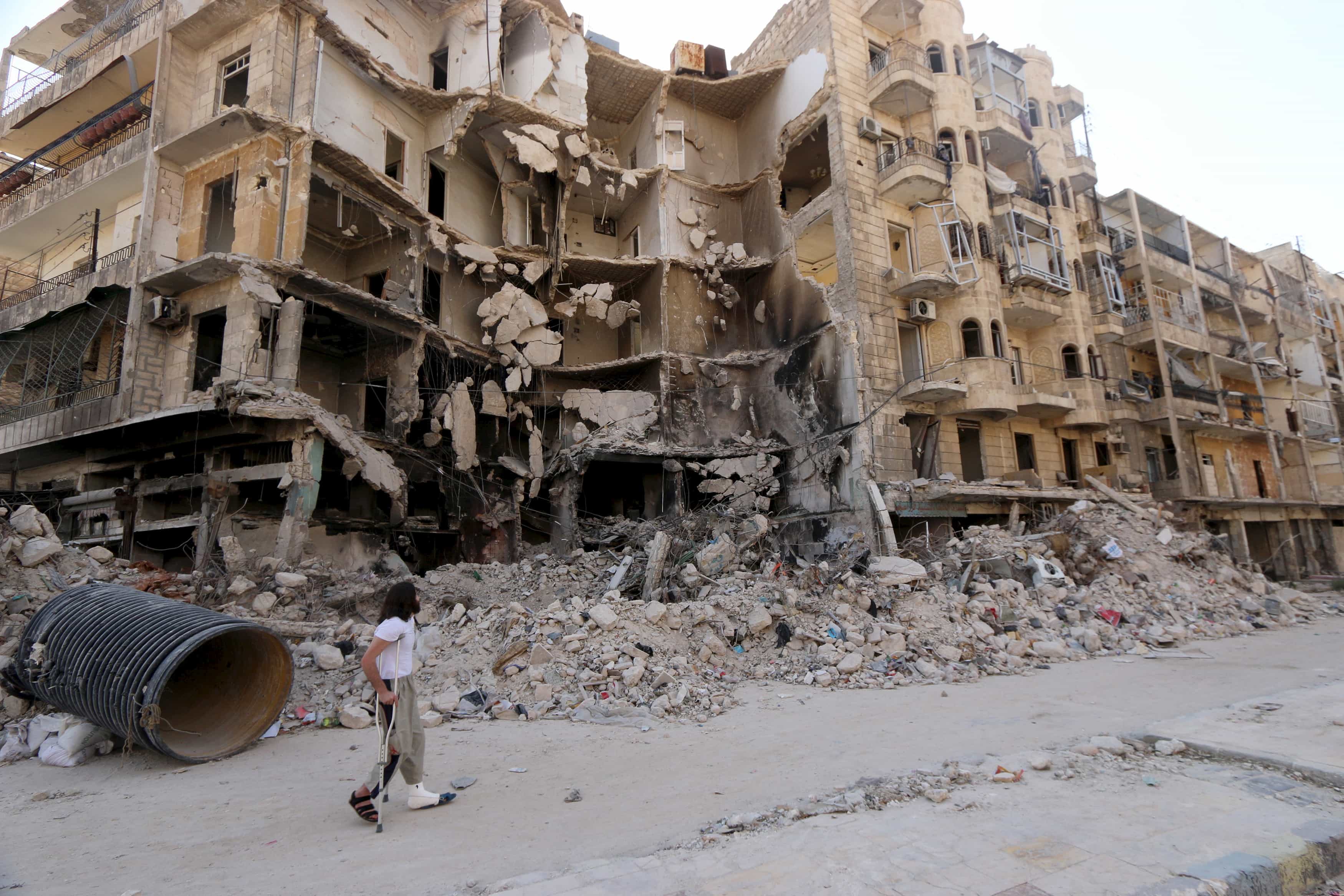 A man walks with the aid of a crutch past damaged buildings in the old city of Aleppo June 27, 2015, REUTERS/Abdalrhman Ismail