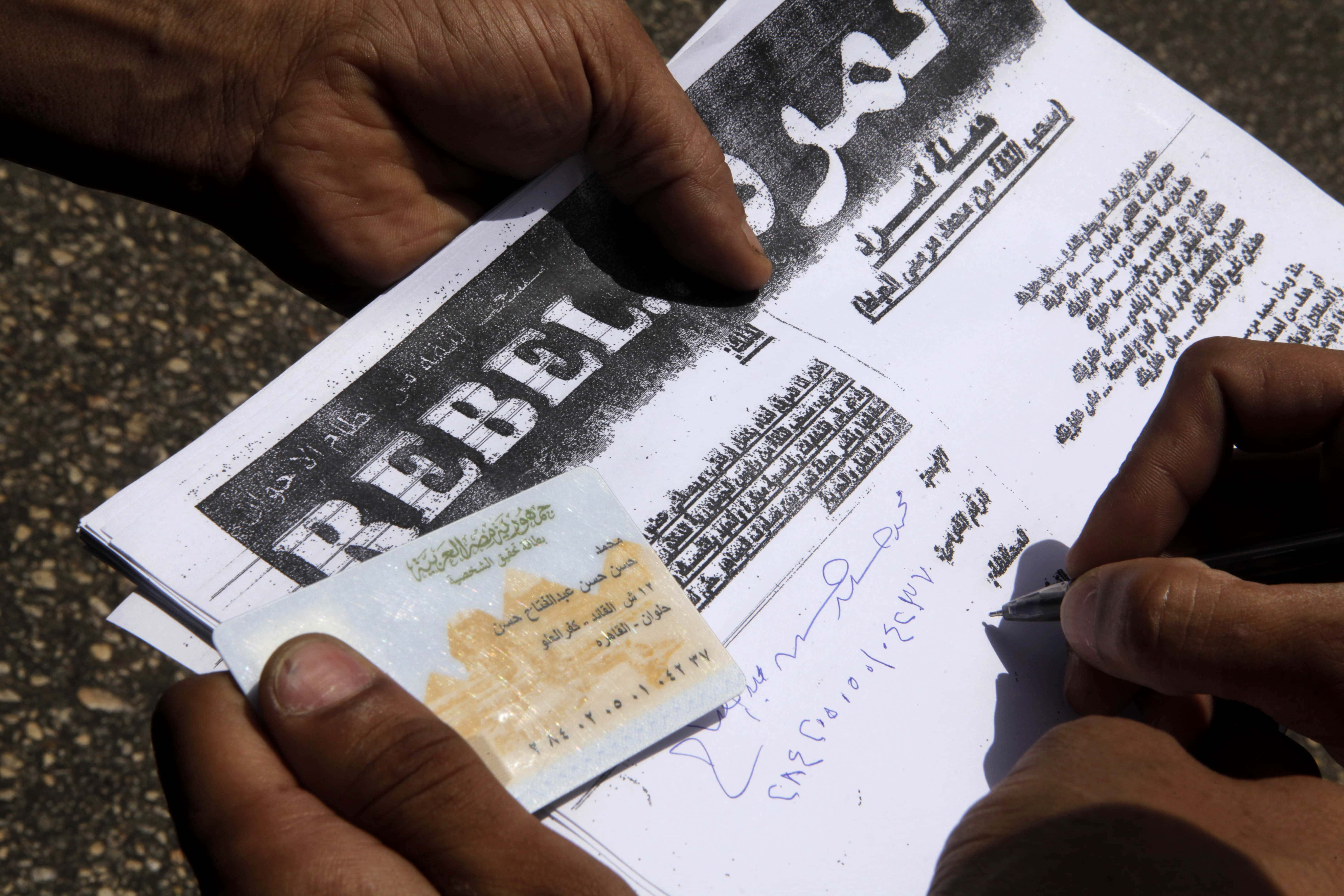 Egyptian Mohammed Hassan signs a paper for the campaign "Tamarod" during a protest in Cairo on 17 May 2013, AP Photo/Amr Nabil