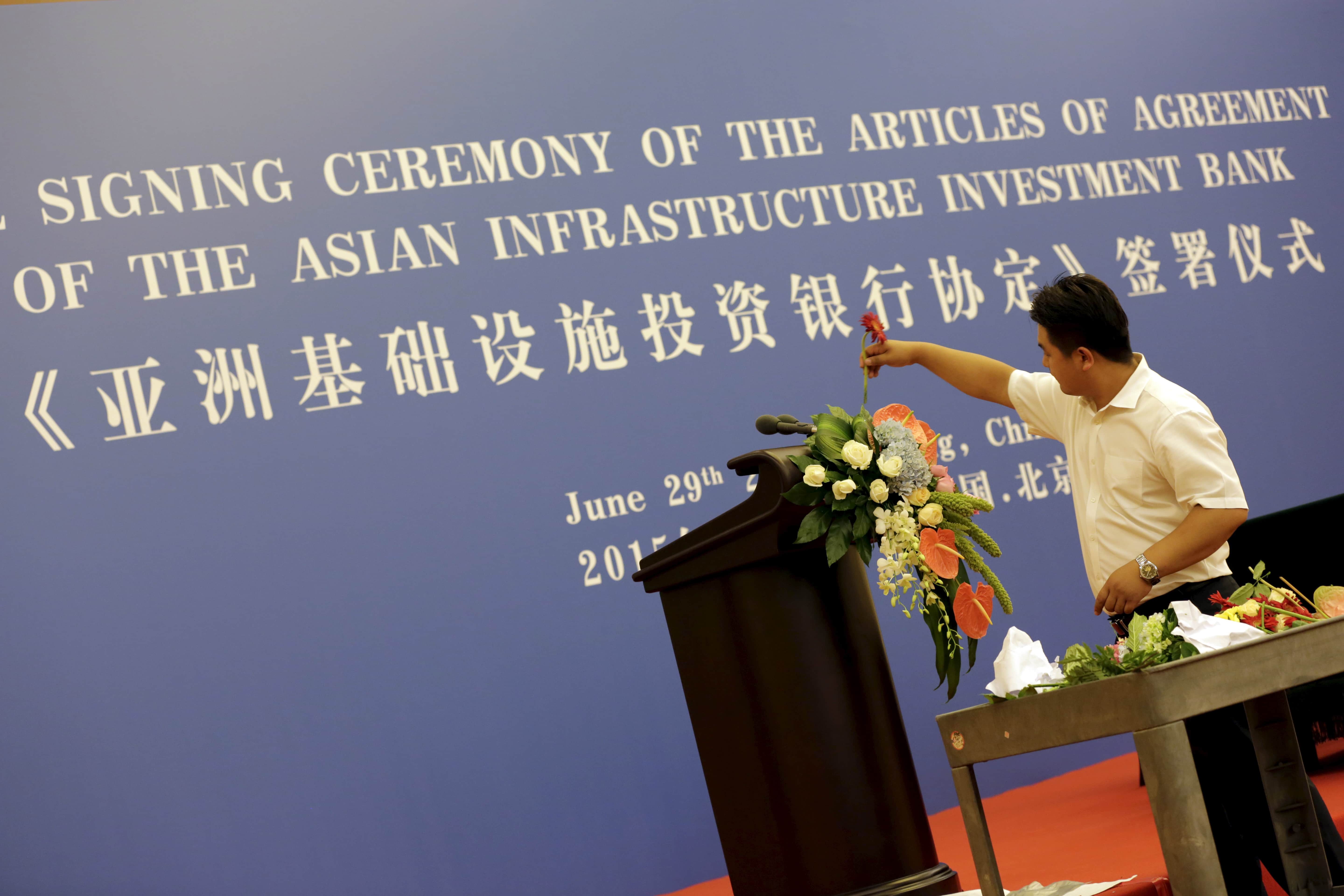 A worker decorates a lectern for a signing ceremony of articles of agreement of the Asian Infrastructure Investment Bank (AIIB), at the Great Hall of the People in Beijing, 29 June 2015, REUTERS/Jason Lee