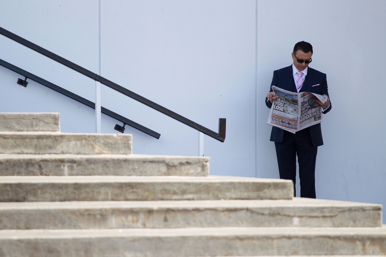 A man reads a newspaper at Flemington Racecourse in Melbourne, Australia, 3 November 2016, Stefan Postles/Getty Images for the VRC