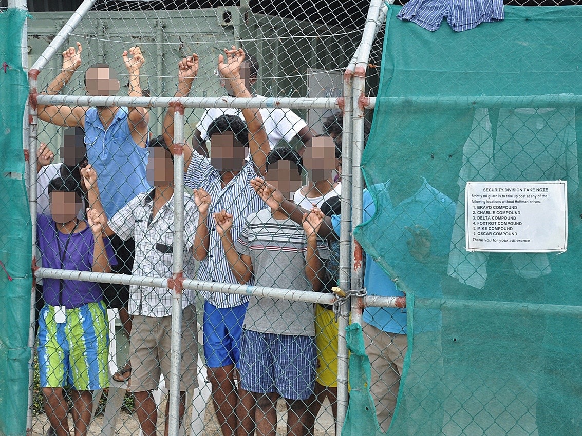 Asylum seekers look through a fence at the Manus Island detention centre in Papua New Guinea, 21 March 2014, AAP/Eoin Blackwell/via REUTERS (Faces pixellated at source)