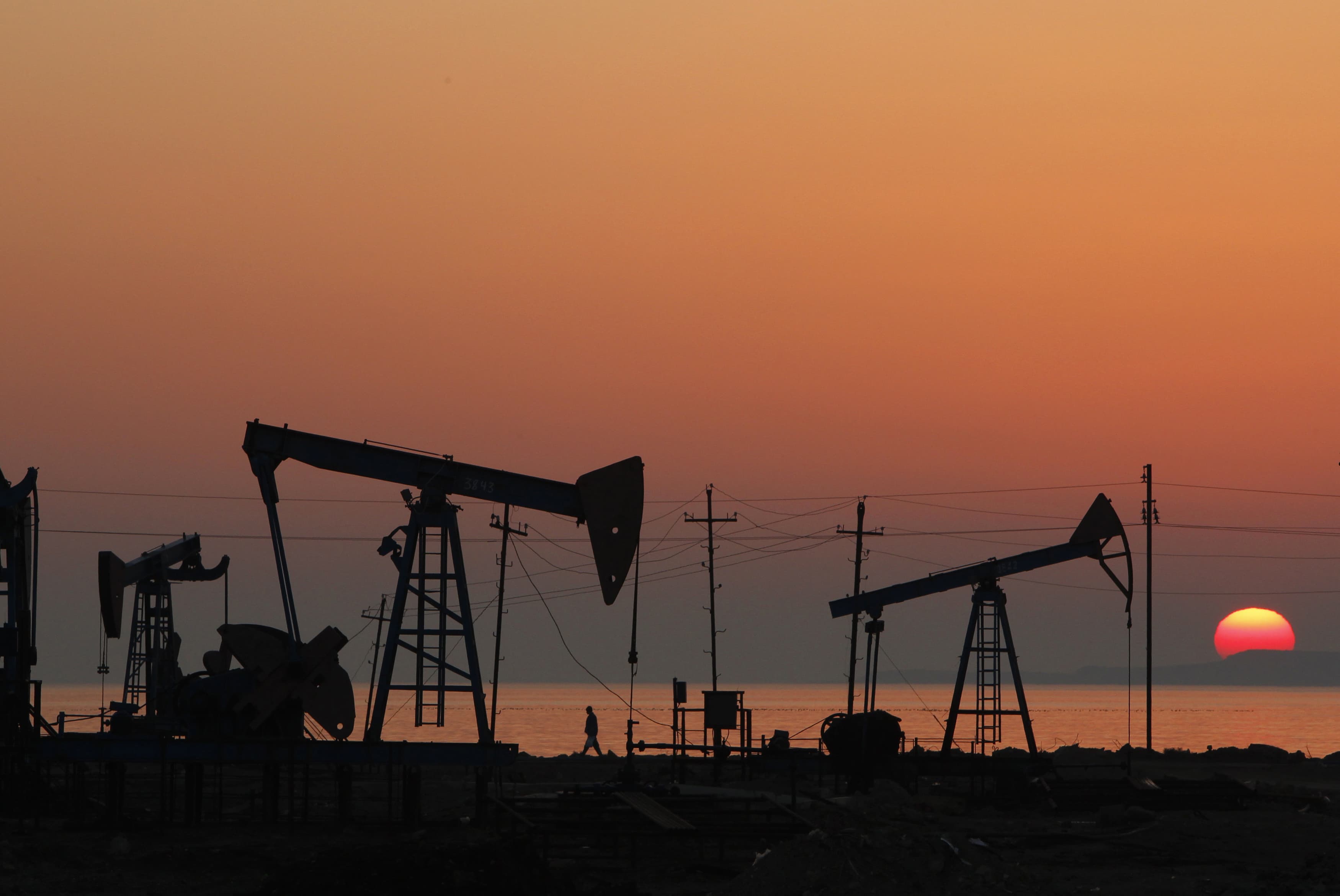 Pump jacks are silhouetted against the rising sun on an oilfield in Baku, Azerbaijan, 24 January 2013 , REUTERS/David Mdzinarishvili
