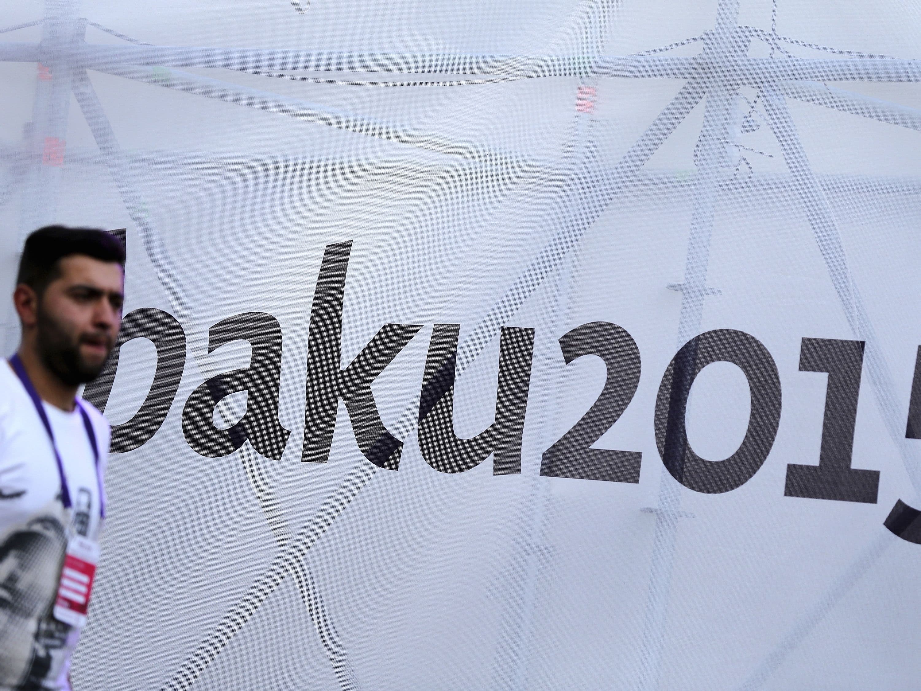 A man walks in front of a banner promoting the European Games in Baku, Azerbaijan, 10 June 2015, REUTERS/Stoyan Nenov