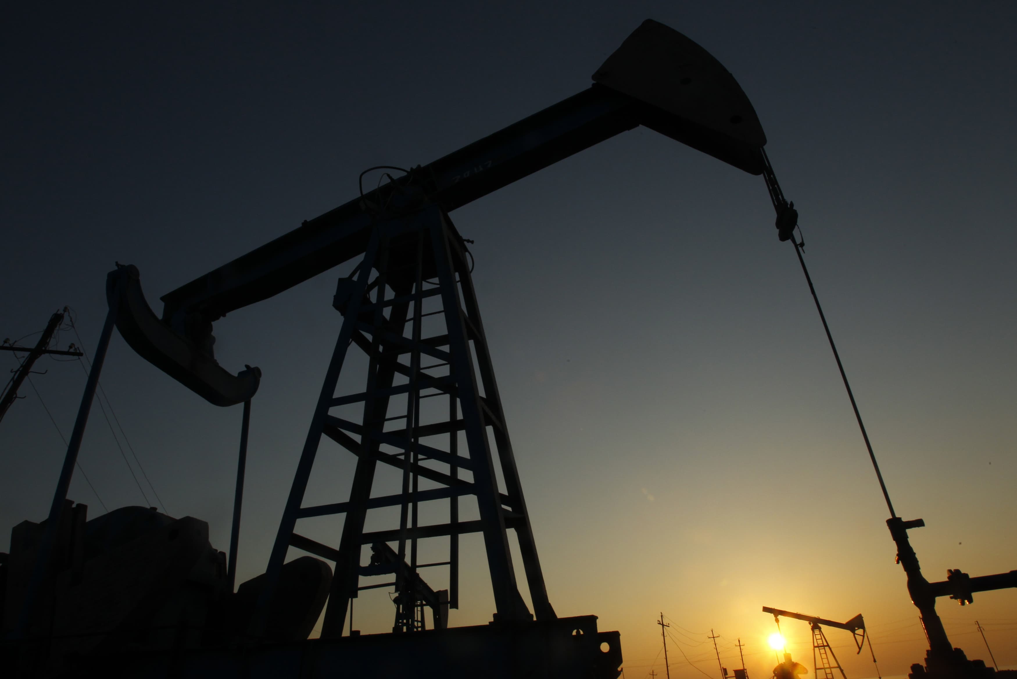 Oil derricks are silhouetted against the rising sun at an oilfield in Baku, 24 January 2013, REUTERS/David Mdzinarishvili