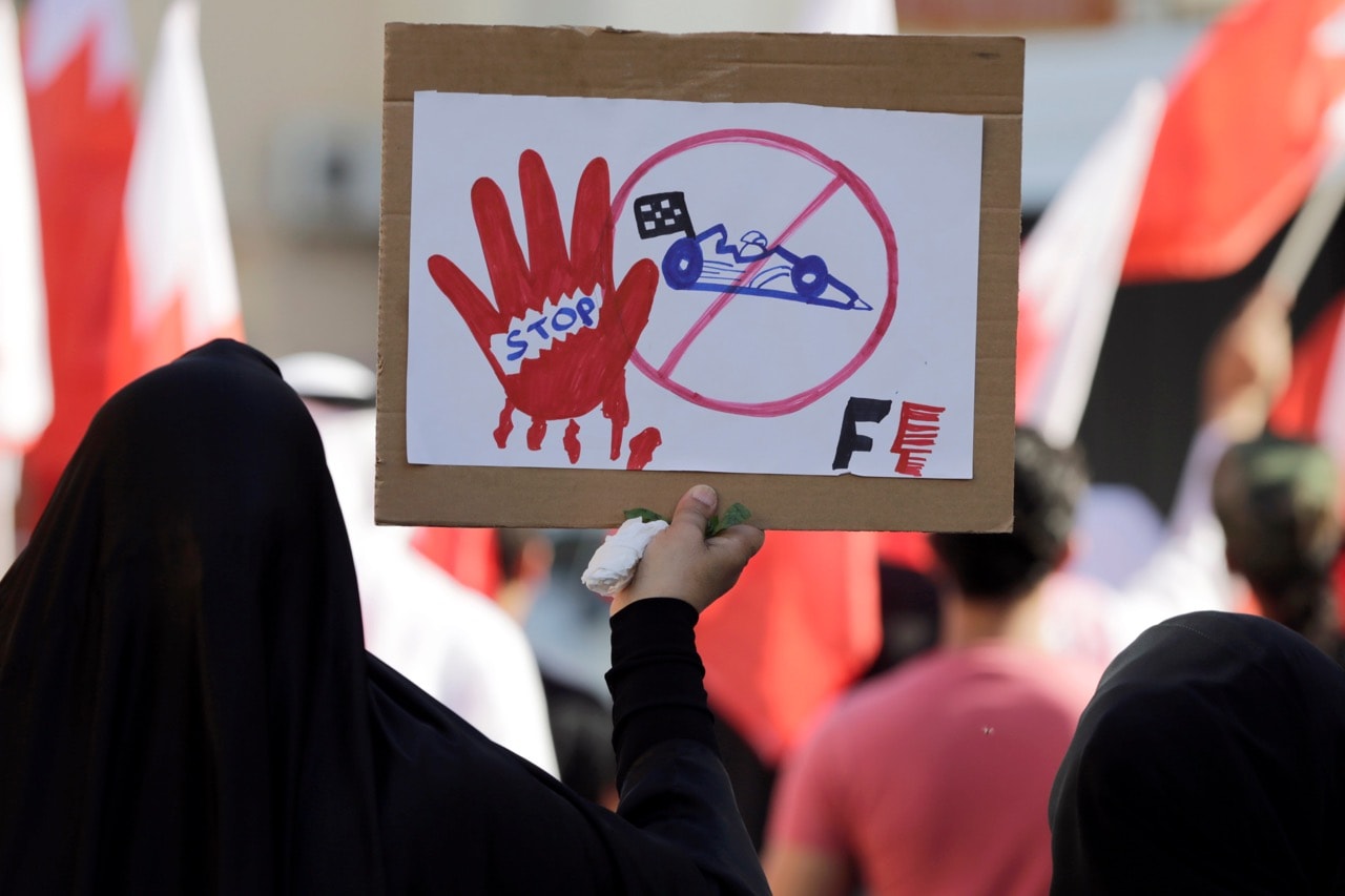An anti-government protester carries a sign opposing the Formula 1 Bahrain Grand Prix, in Daih, Bahrain, 3 April 2016, AP Photo/Hasan Jamali
