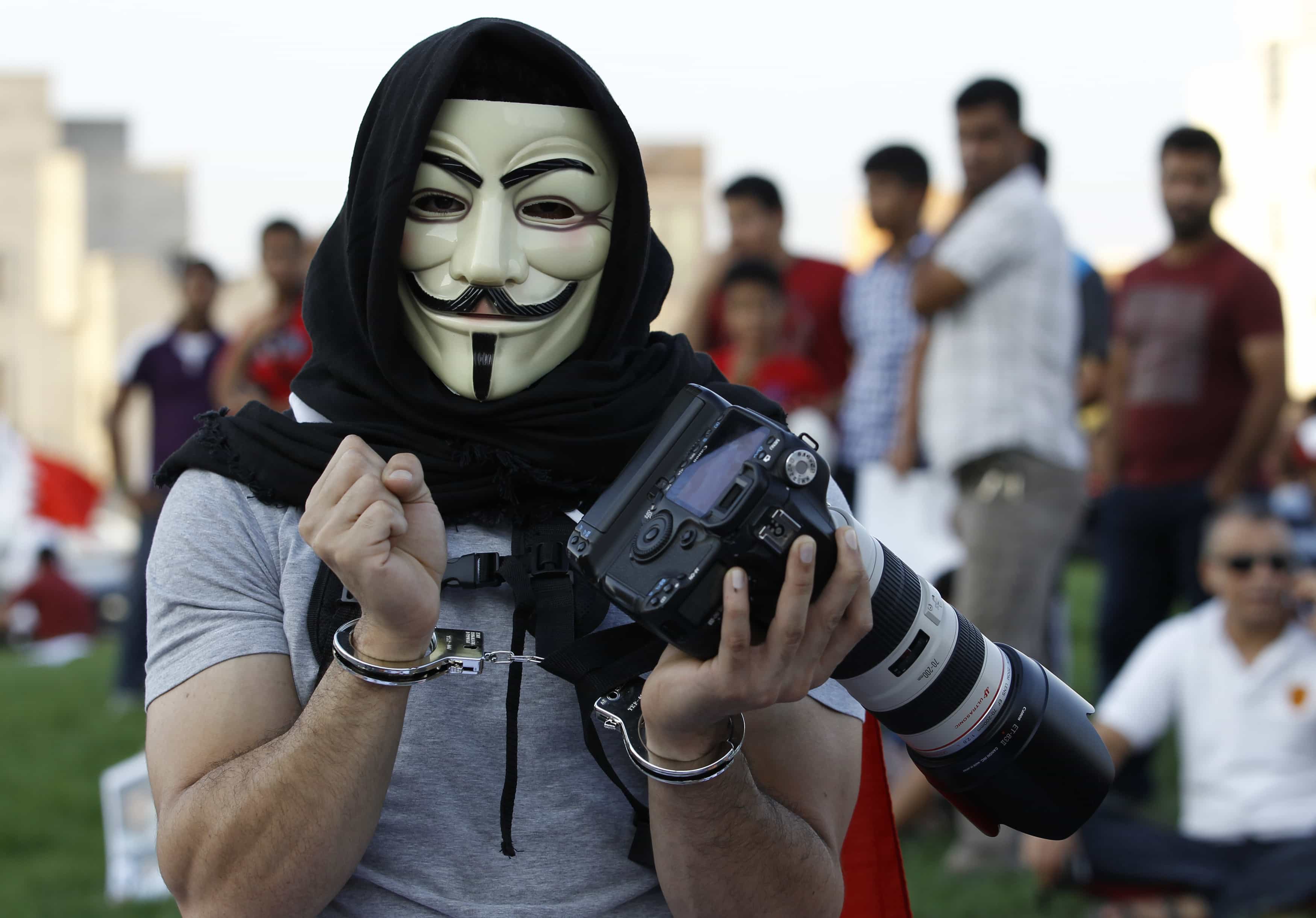 A protester wearing a Guy Fawkes mask poses with a camera with his hands cuffed in a show of support for arrested photographers in Bahrain, REUTERS/Hamad I Mohammed