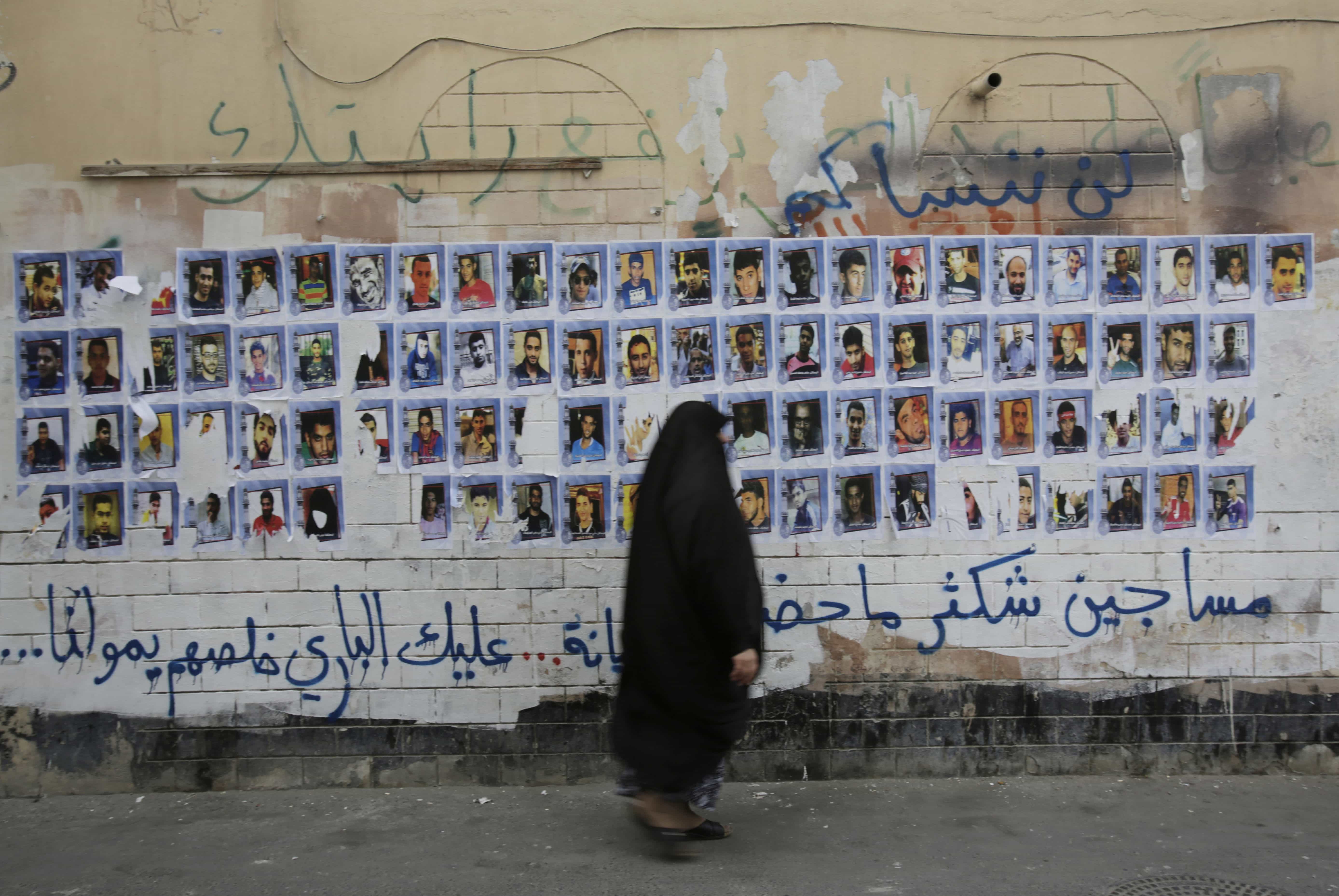 A Bahraini woman walks past images of political prisoners plastered on a wall in Sanabis, Bahrain, on 22 October 2015, as she makes her way to attend events for the Shiite religious occasion of Ashura, AP Photo/Hasan Jamali