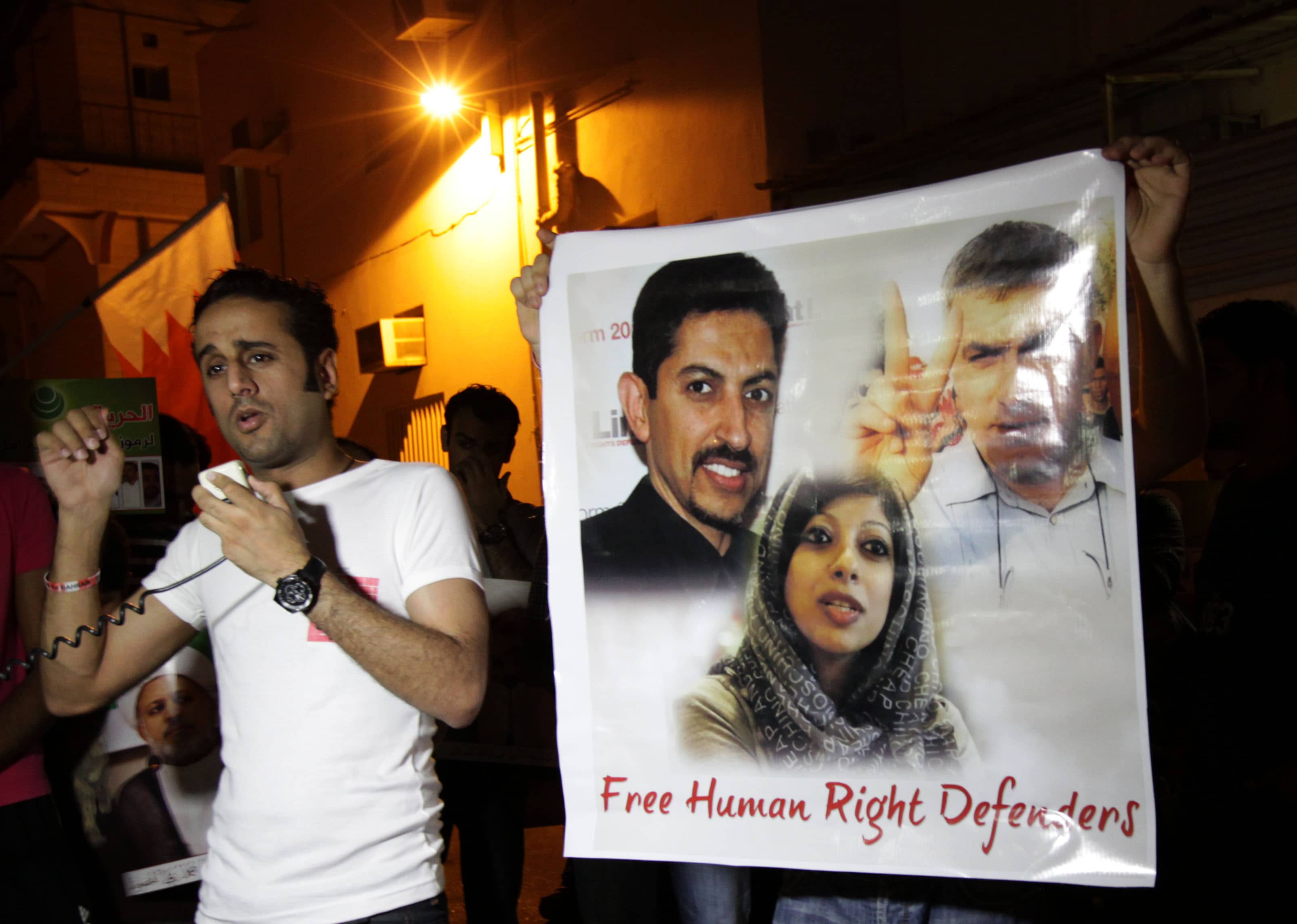 In this photo taken on 12 August 2012, activist Said Yousif al-Muhafdah speaks to protesters in Bahrain, calling for freedom for jailed rights activists seen on the poster at right, Abdul Hadi al-Khawaja, Nabeel Rajab and Zainab al-Khawaja, AP Photo/Hasan Jamali