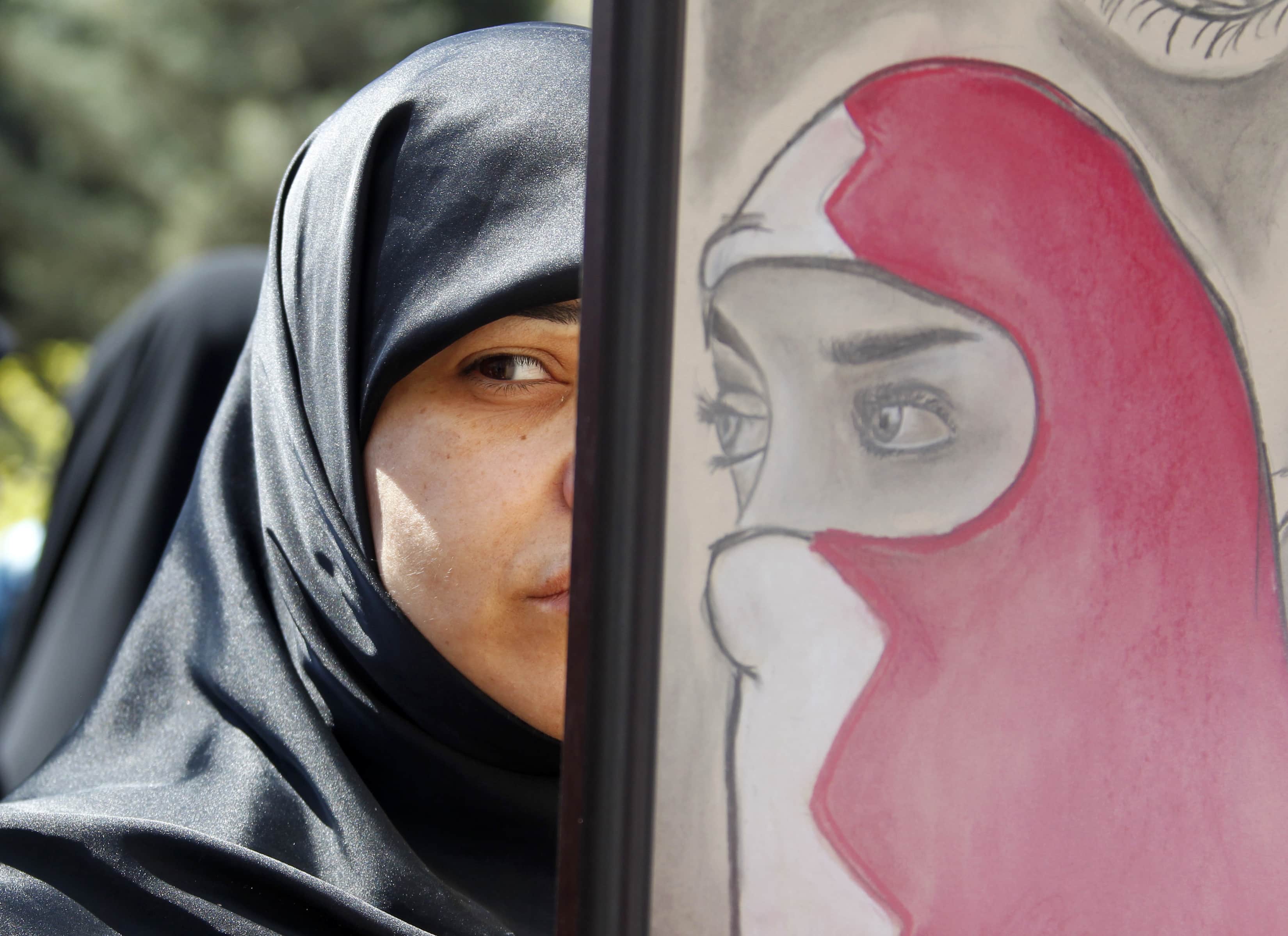 A protester carries a picture of a woman wearing the colours of Bahrain's national flag during a protest near the United Nations headquarters in Beirut April 13, 2012, REUTERS/Sharif Karim