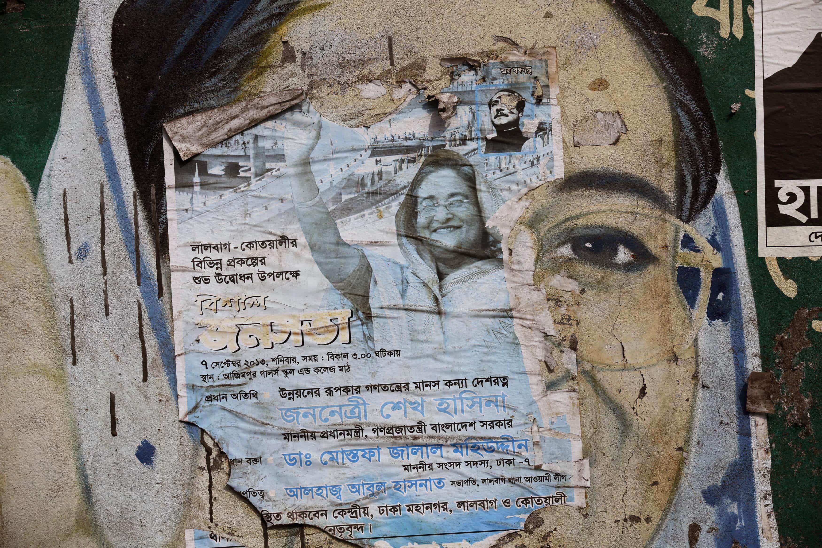 A torn election campaign poster of Bangladesh's Prime Minister Sheikh Hasina is seen on top of a mural depicting her in Dhaka, 4 January 2014, REUTERS/Andrew Biraj