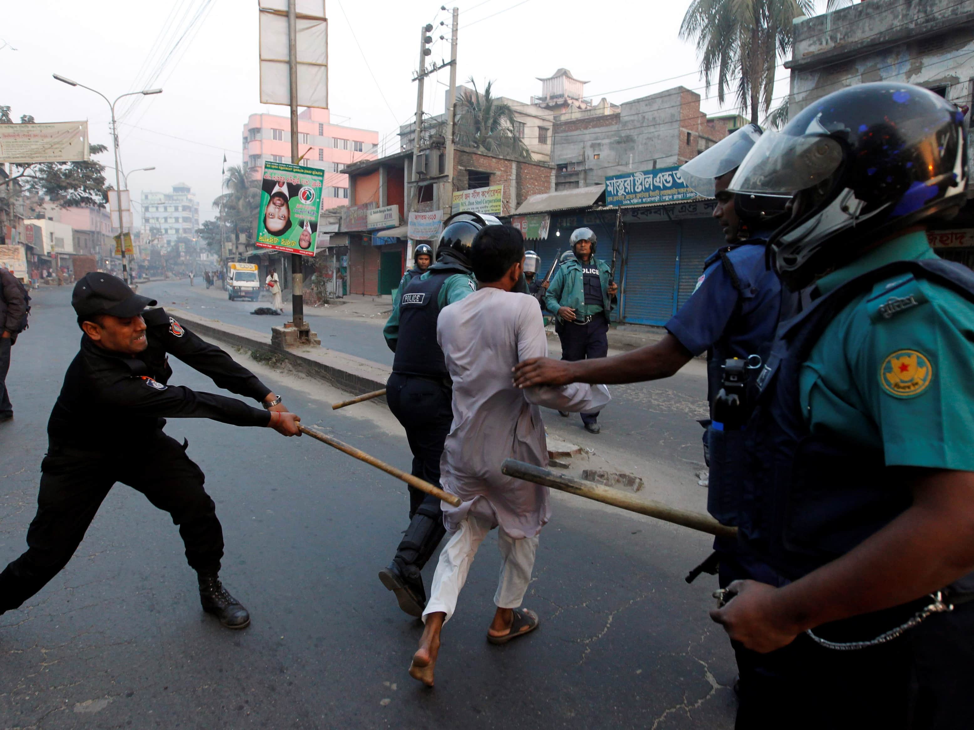 A member of the Rapid Action Battalion (RAB) swings a baton at a Jamaat-e-Islam activist on 5 February 2013, during a day-long strike in Dhaka, REUTERS/Andrew Biraj