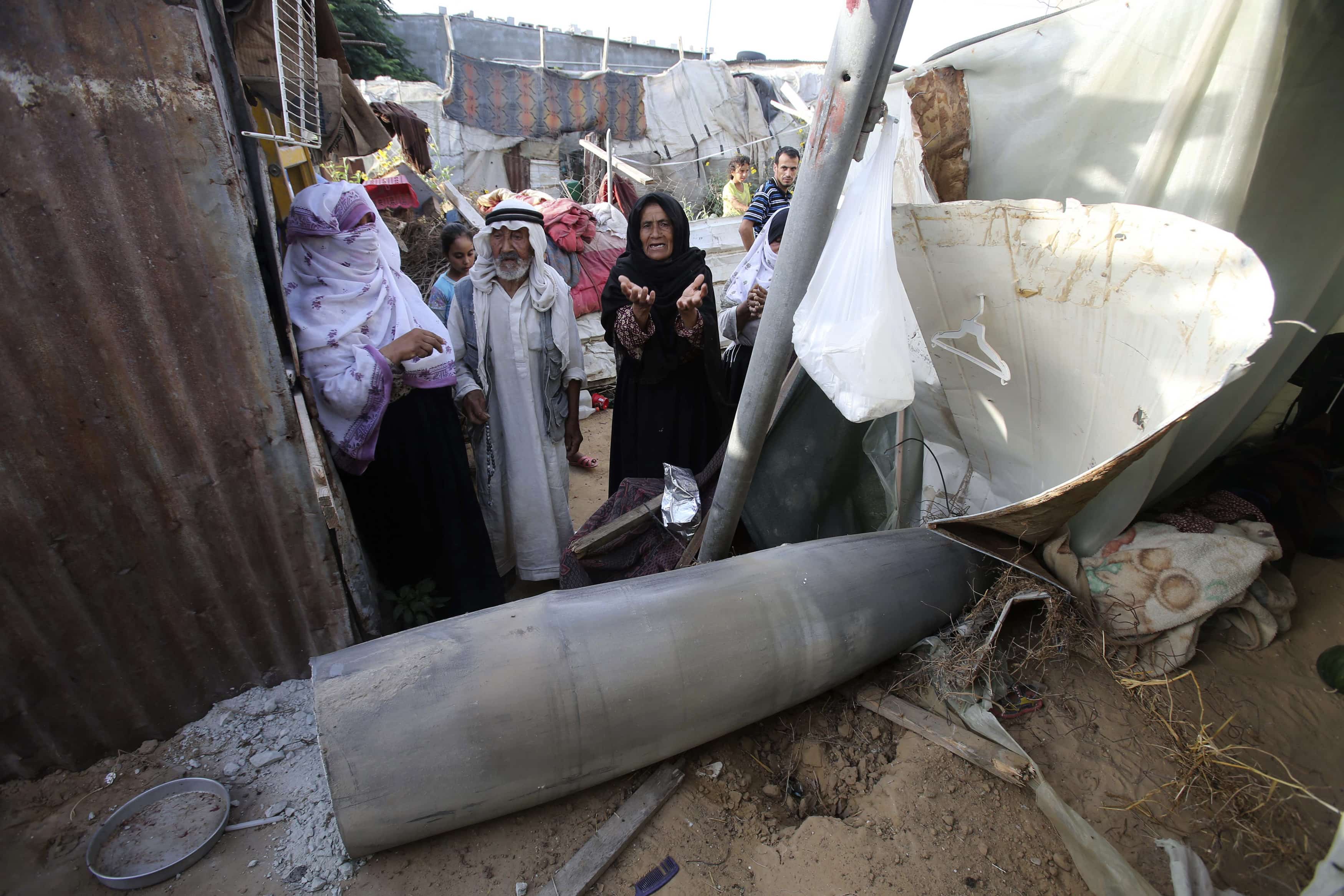 A Palestinian woman gestures as she stands behind a missile which witnesses said was fired by Israeli aircraft, at a shack belonging to Bedouins in Rafah, in the southern Gaza Strip on 13 July 2014, REUTERS/Ibraheem Abu Mustafa