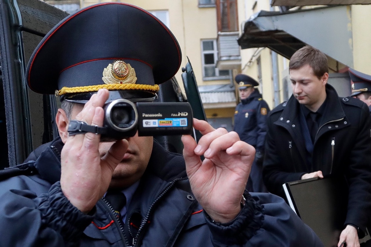 A Belarusian Interior Ministry officer films nearby journalists, near the office of Belsat channel as they conduct a search in the office in Minsk, 31 March 2017, AP Photo/Sergei Grits