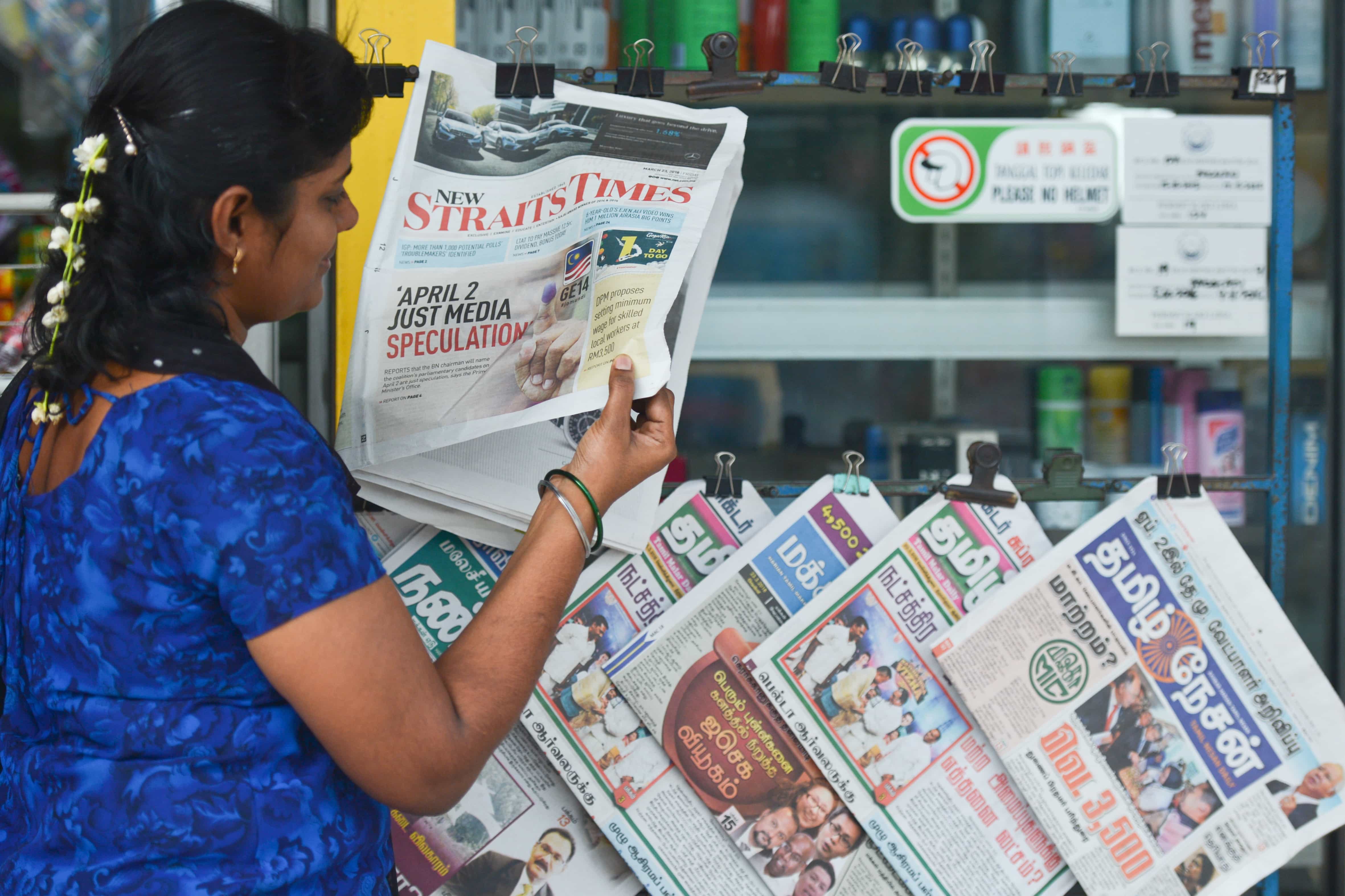 A woman browsing newspapers in in Tanjung Malim, Malaysia, 23 March 2018, Artur Widak/NurPhoto via Getty Images