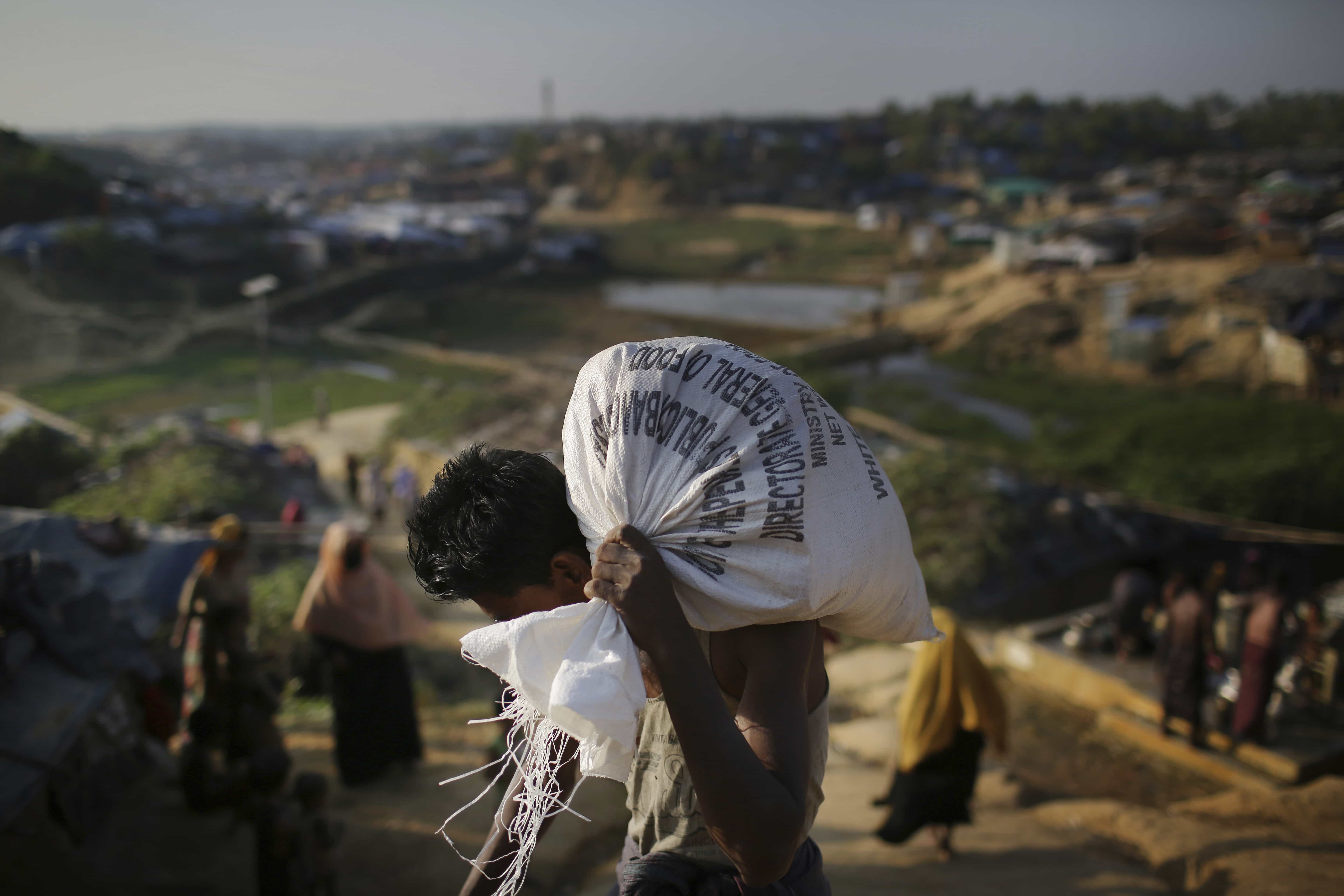 A Rohingya Muslim man carries a sack of rice as he makes his way through Kutupalong refugee camp in Bangladesh, 19 November 2017, AP Photo/Wong Maye-E