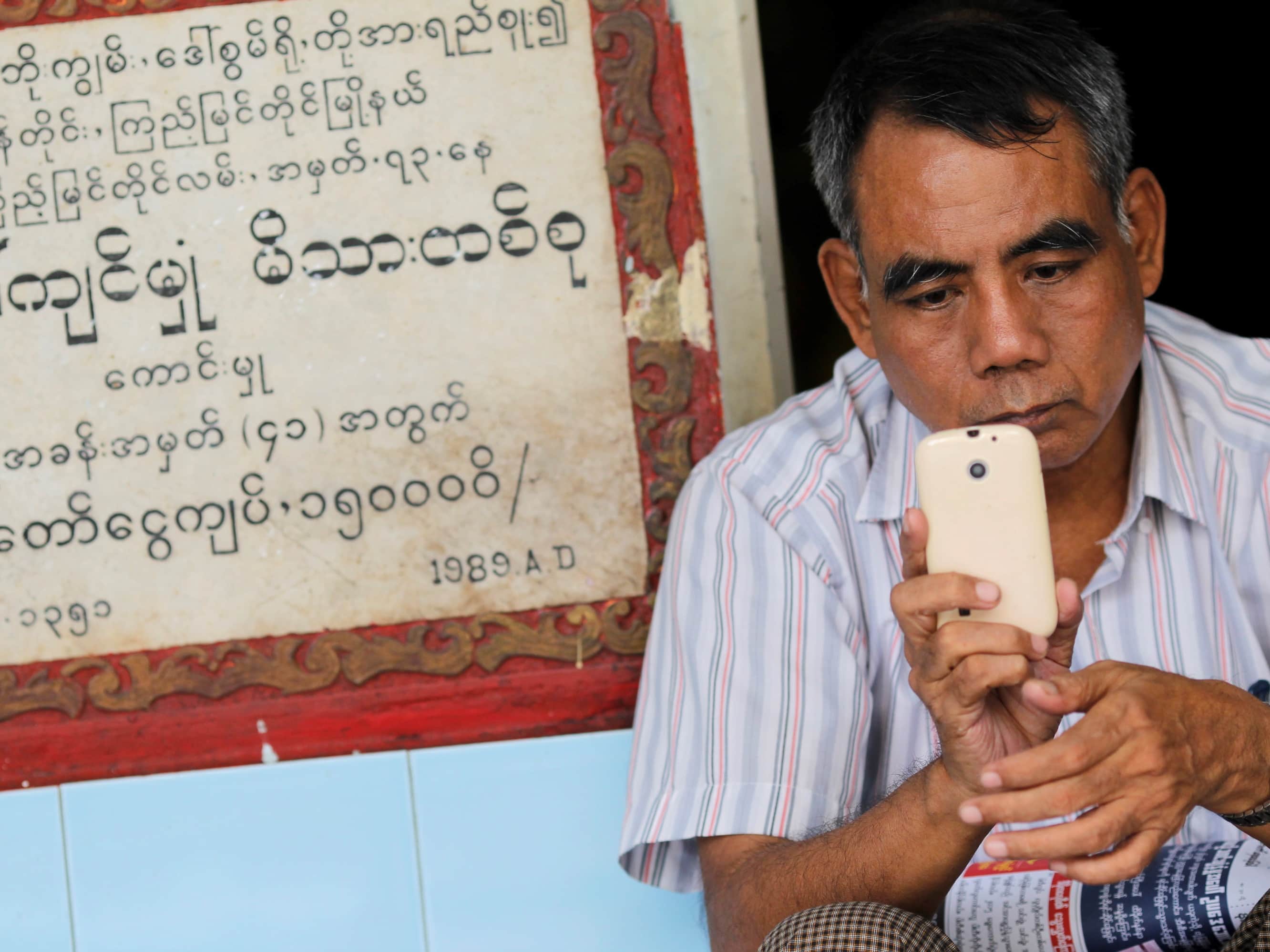 A man uses his mobile phone on the side of a street in Yangon, 7 March 2013, REUTERS/Soe Zeya Tun