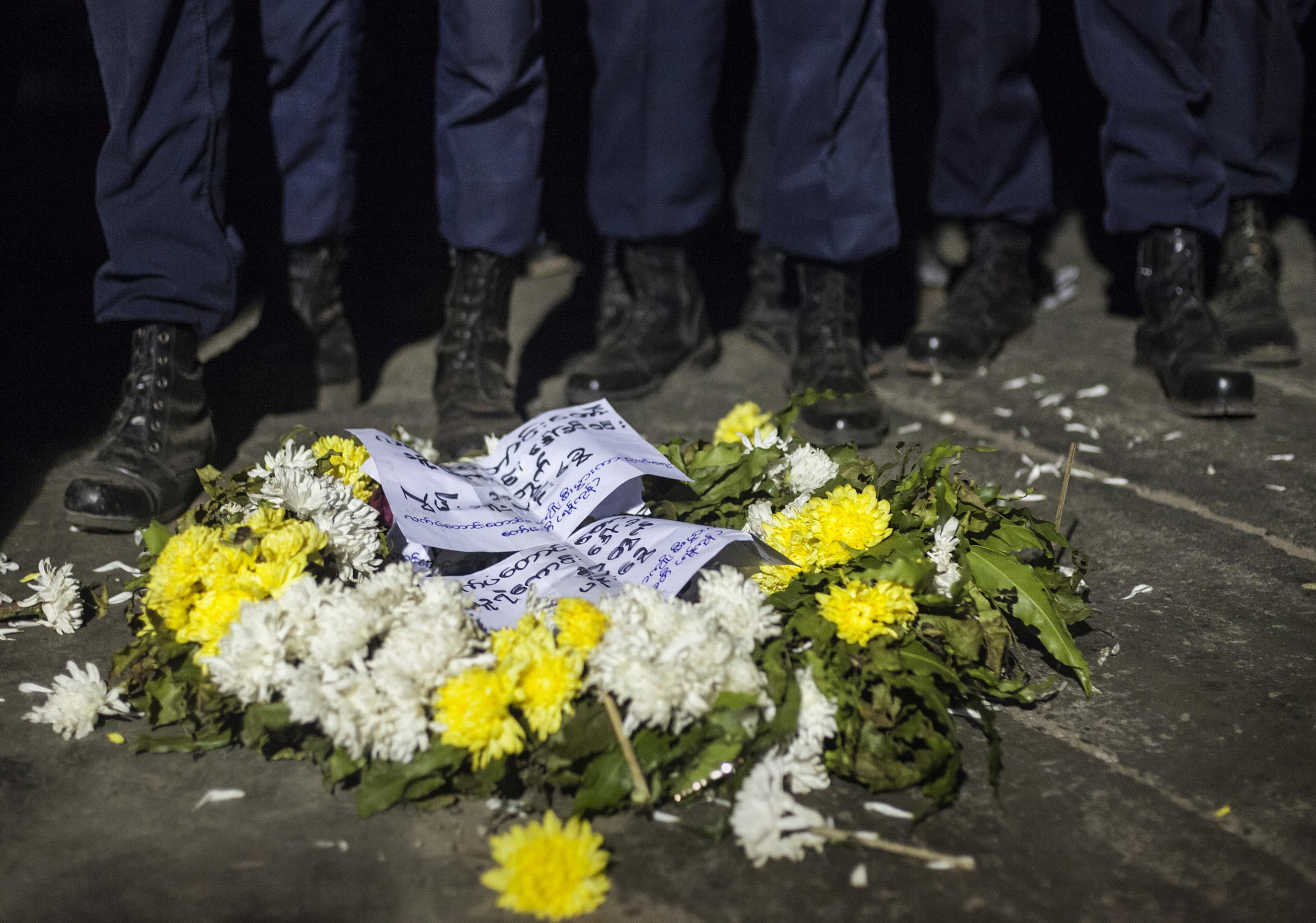 Police officers stand by a wreath for protester Daw Khin Win, near the Chinese embassy in Yangon, 29 December 2014, REUTERS/Minzayar