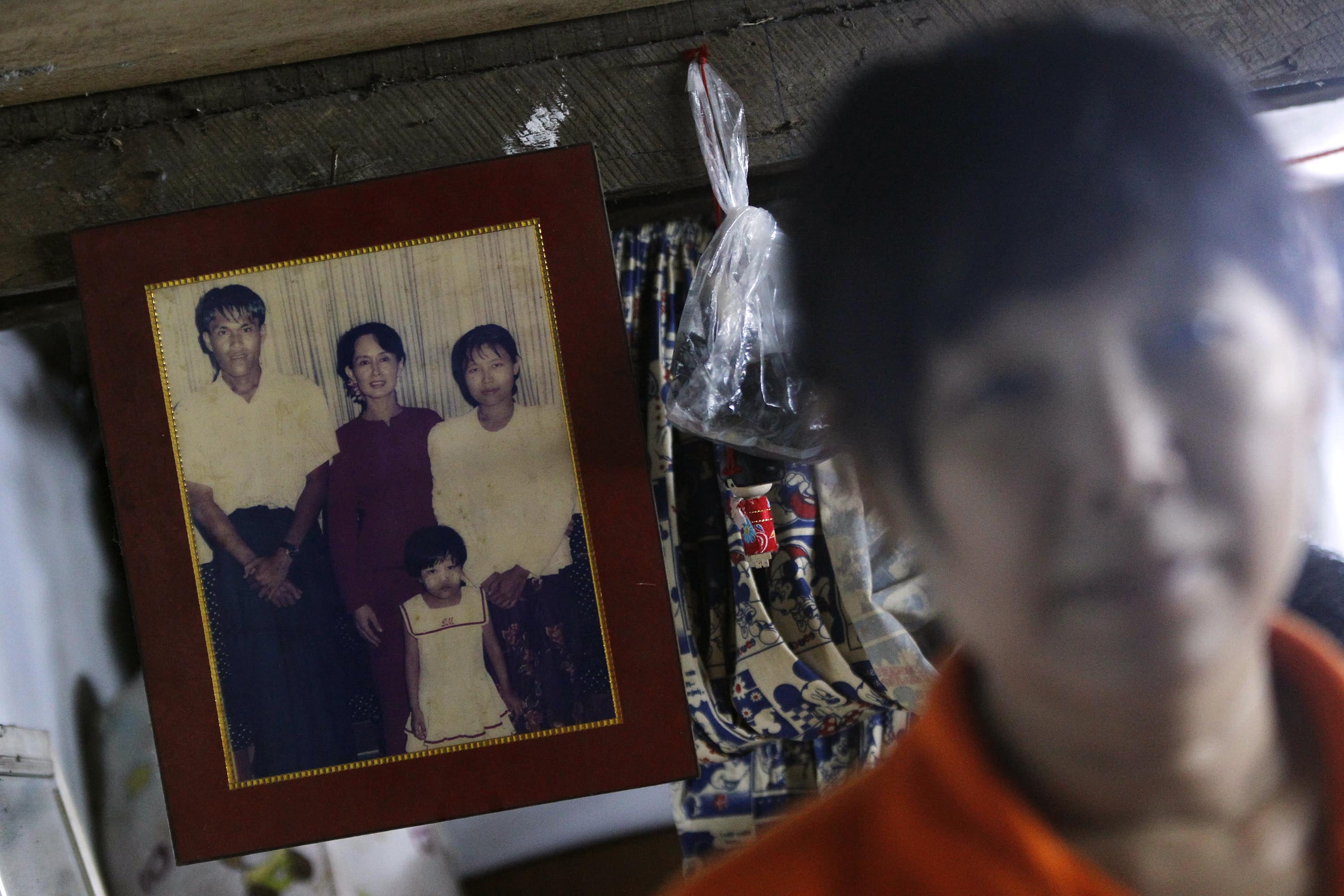 Than Dar, the wife of slain journalist Par Gyi, stands in front of a family photograph showing herself, her husband and daughter posing with Aung San Suu Kyi, during a Reuters interview at her home in Yangon, 28 October 2014, REUTERS/Soe Zeya Tun