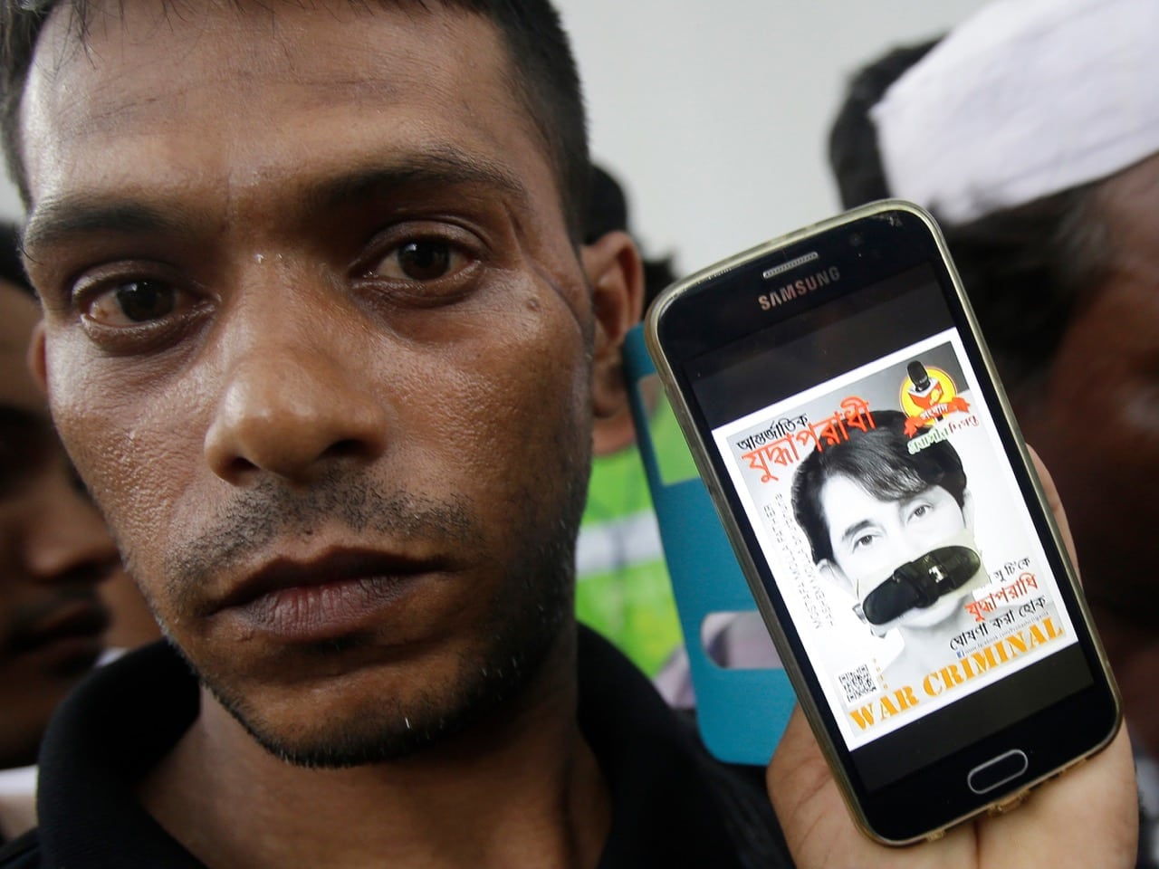 On 25 November 2016, a Rohingya protester displays a portrait of Aung San Suu Kyi with her mouth covered with a sandal during a demonstration in front of the Burmese Embassy in Bangkok, Thailand, against the persecution of Muslim Rohingya in Burma, AP Photo/Sakchai Lalit