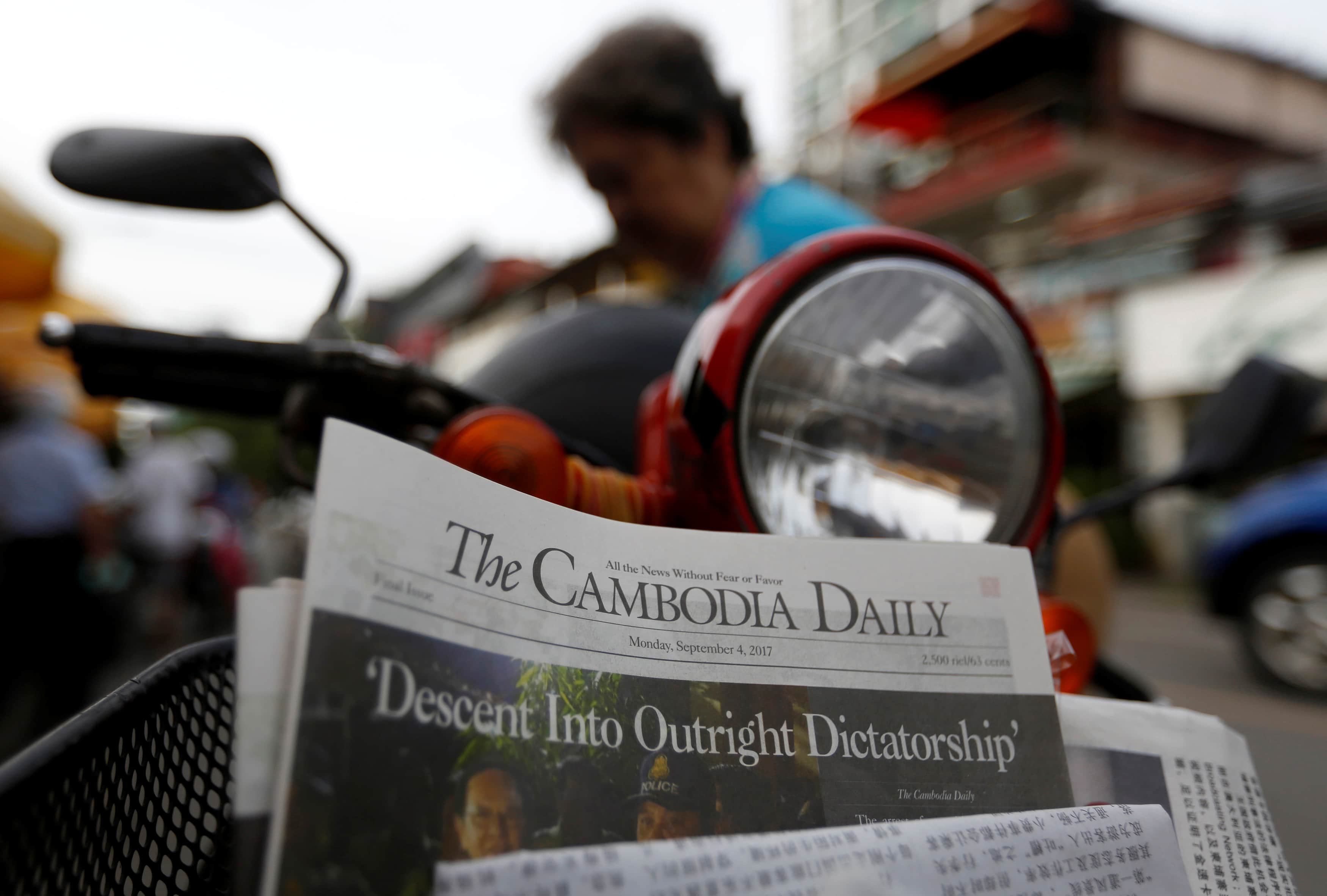 A woman buys the final issue of The Cambodia Daily newspaper at a store along a street in Phnom Penh, Cambodia, September 4, 2017. , REUTERS/Samrang Pring