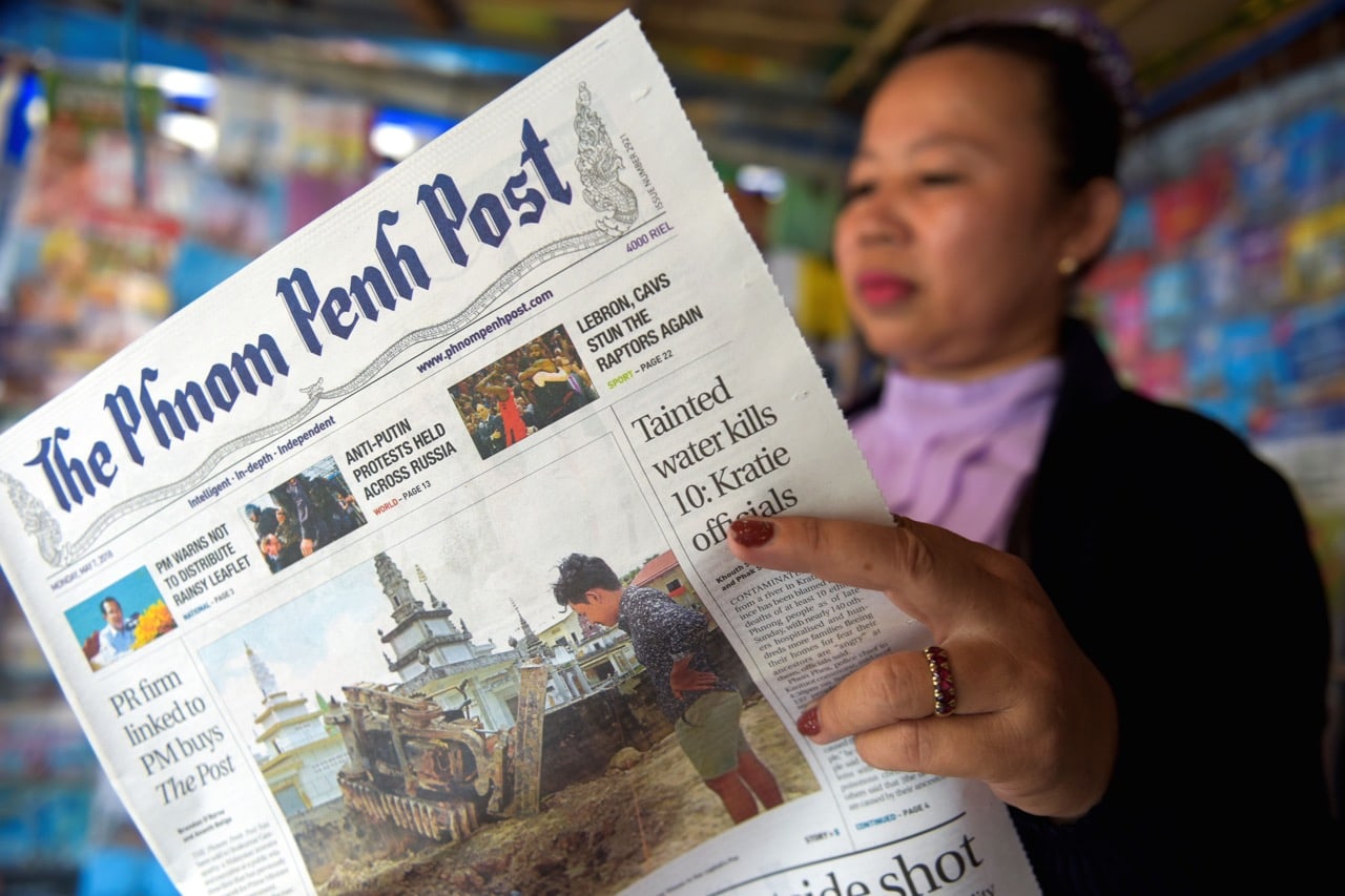 A vendor reads the "Phnom Penh Post" newspaper at her newstand in Phnom Penh, Cambodia, May 2018, TANG CHHIN SOTHY/AFP/Getty Images