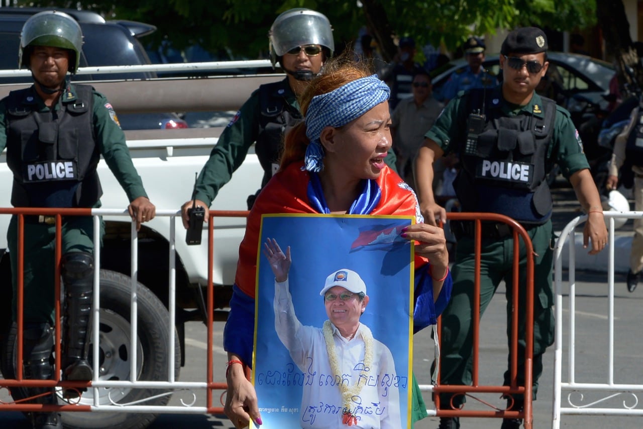 A Cambodia National Rescue Party (CNRP) supporter holds a placard with a portrait of CNRP leader Kem Sokha as police block a street during a protest outside the court of appeal in Phnom Penh, 26 September 2017, TANG CHHIN SOTHY/AFP/Getty Images