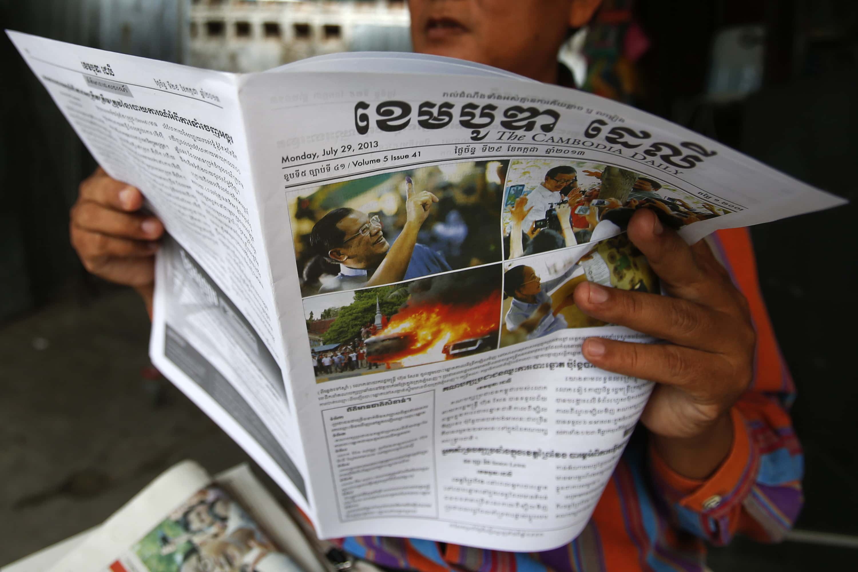A man reads a newspaper with the front page story about the previous day's election in Phnom Penh, 29 July 2013, REUTERS/Samrang Pring