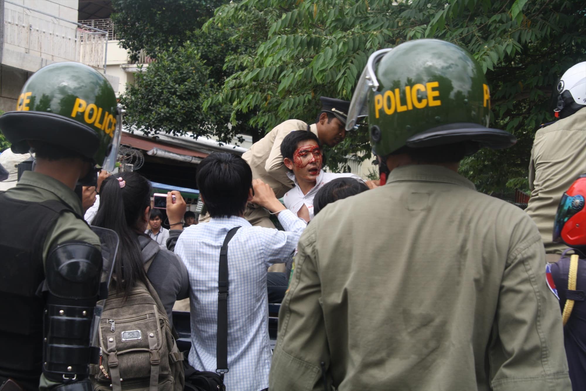 A bloodied Long Panha is put in the back of a police van today at Wat Botum, CCHR