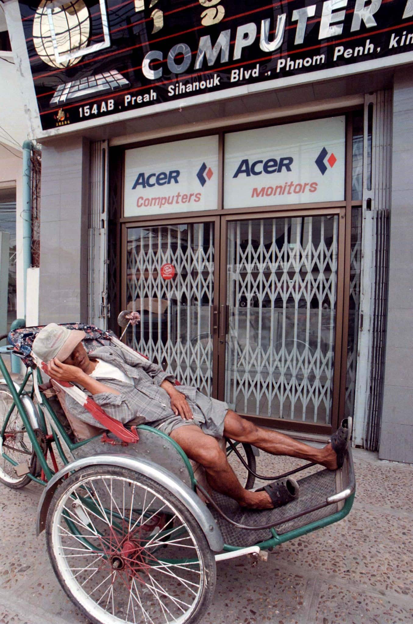 A Cambodian cyclo-driver sleeps outside a computer shop in Phnom Penh, Reuters