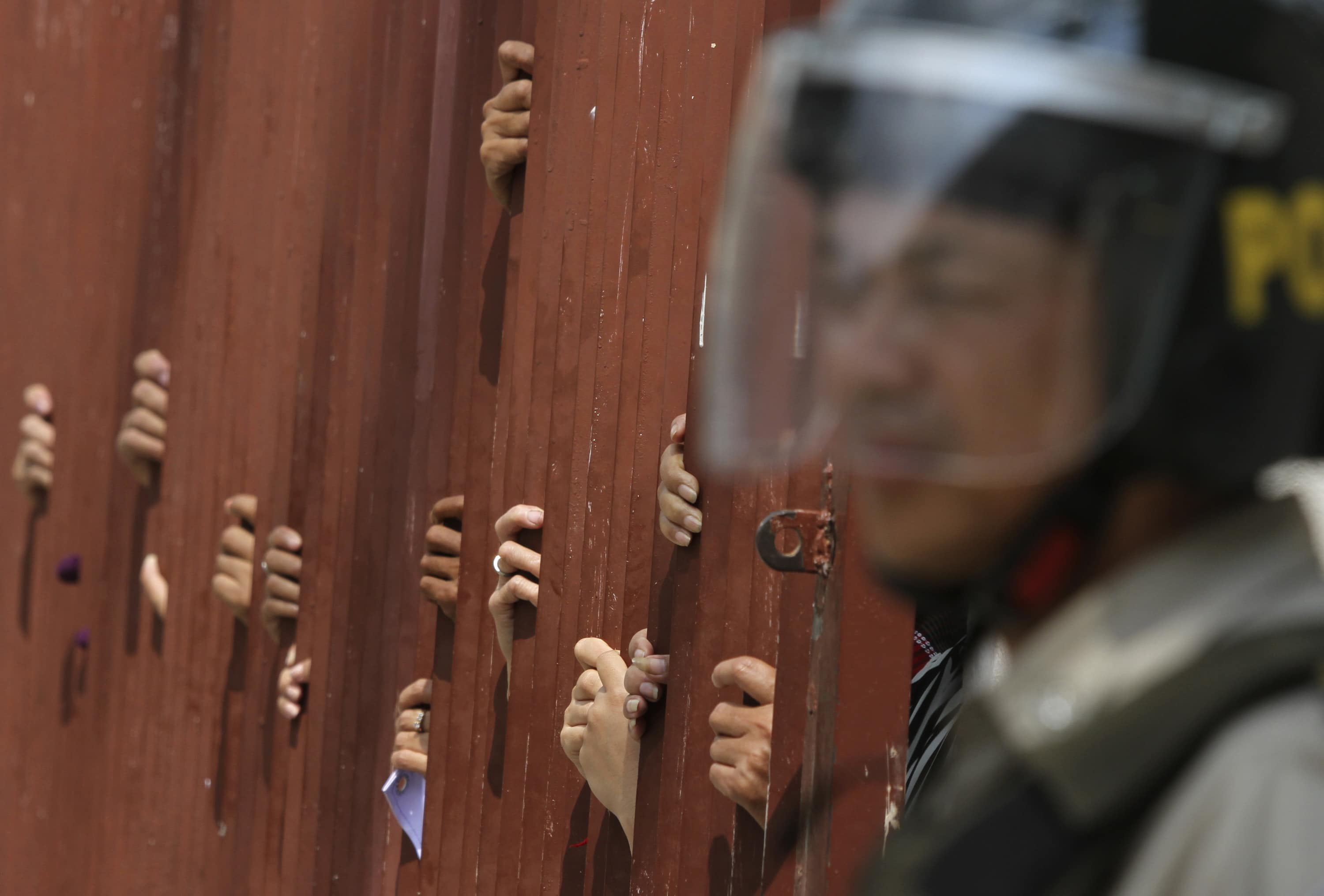 A police officer blocks a gate at the Appeal Court during a protest in Phnom Penh, 11 February 2014. The court denied bail to 21 rights defenders and garment workers jailed in January, REUTERS/Samrang Pring