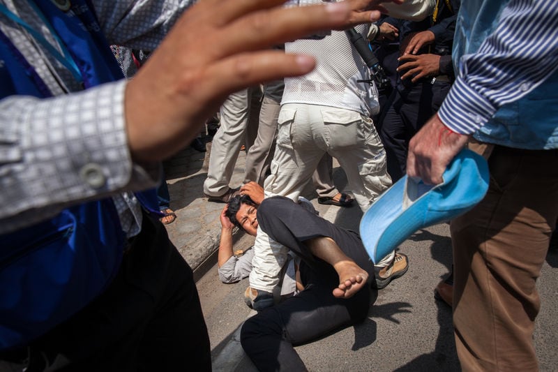 Human rights monitors try to stop a passer-by from getting beaten. Police and 'auxiliary police' pulled him off his motorbike minutes after hundreds of people protested in front of Freedom Park in Phnom Penh on 1 May 2014, Demotix/Erika Pineros