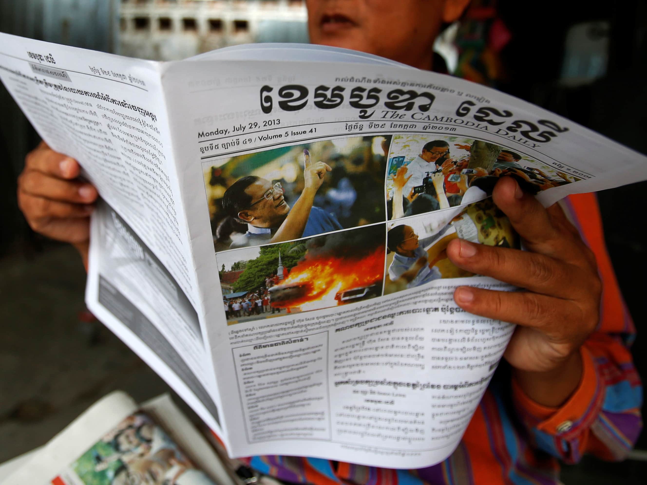 On 29 July 2013, a man in Phnom Penh reads a newspaper with a front page story about the previous day's election, REUTERS/Samrang Pring