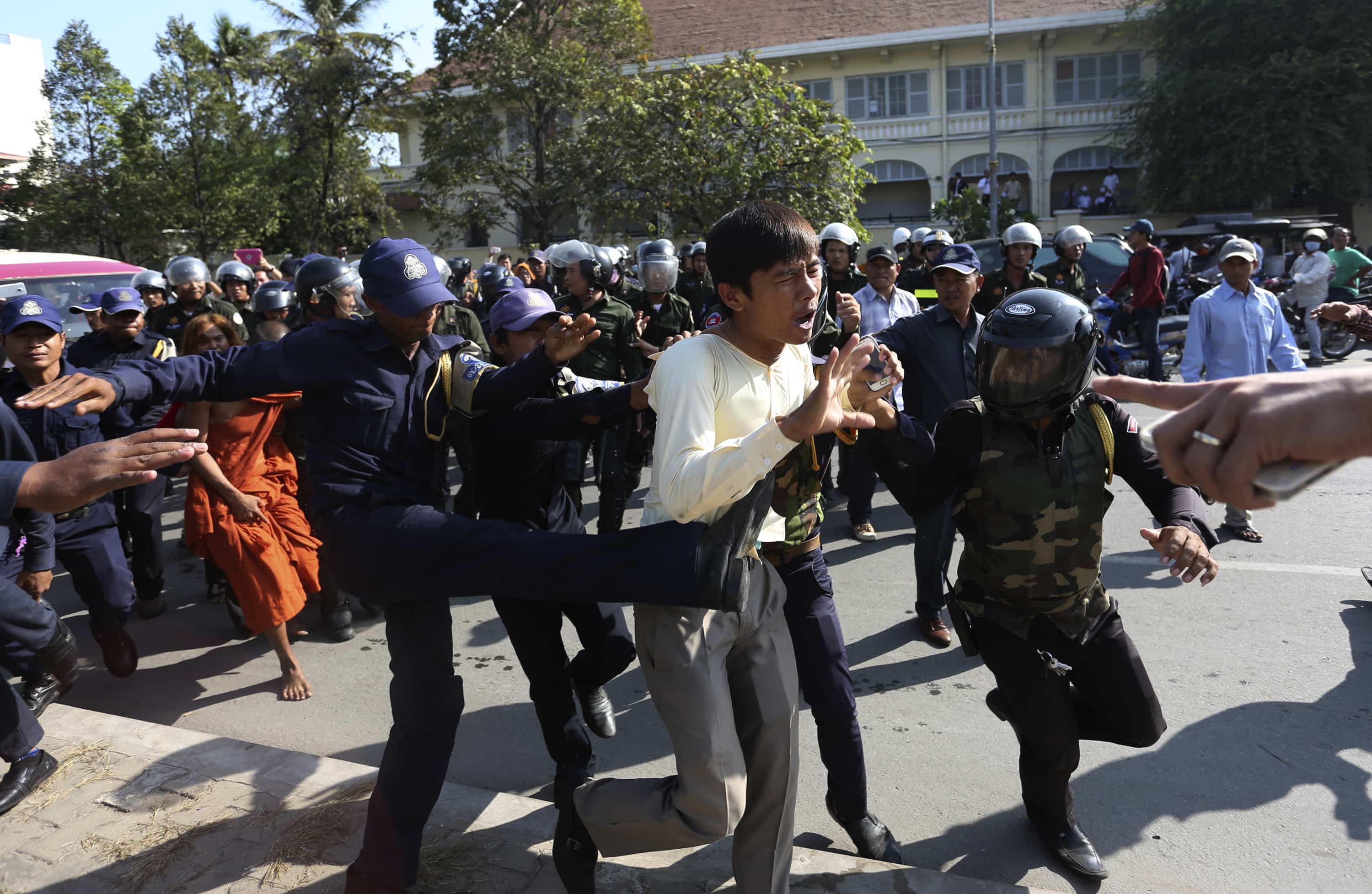 A former Boeng Kak lake resident is kicked by a police officer during a demonstration in Phnom Penh protesting forced evictions linked to a World Bank financed project on 24 December 2014, REUTERS/Stringer