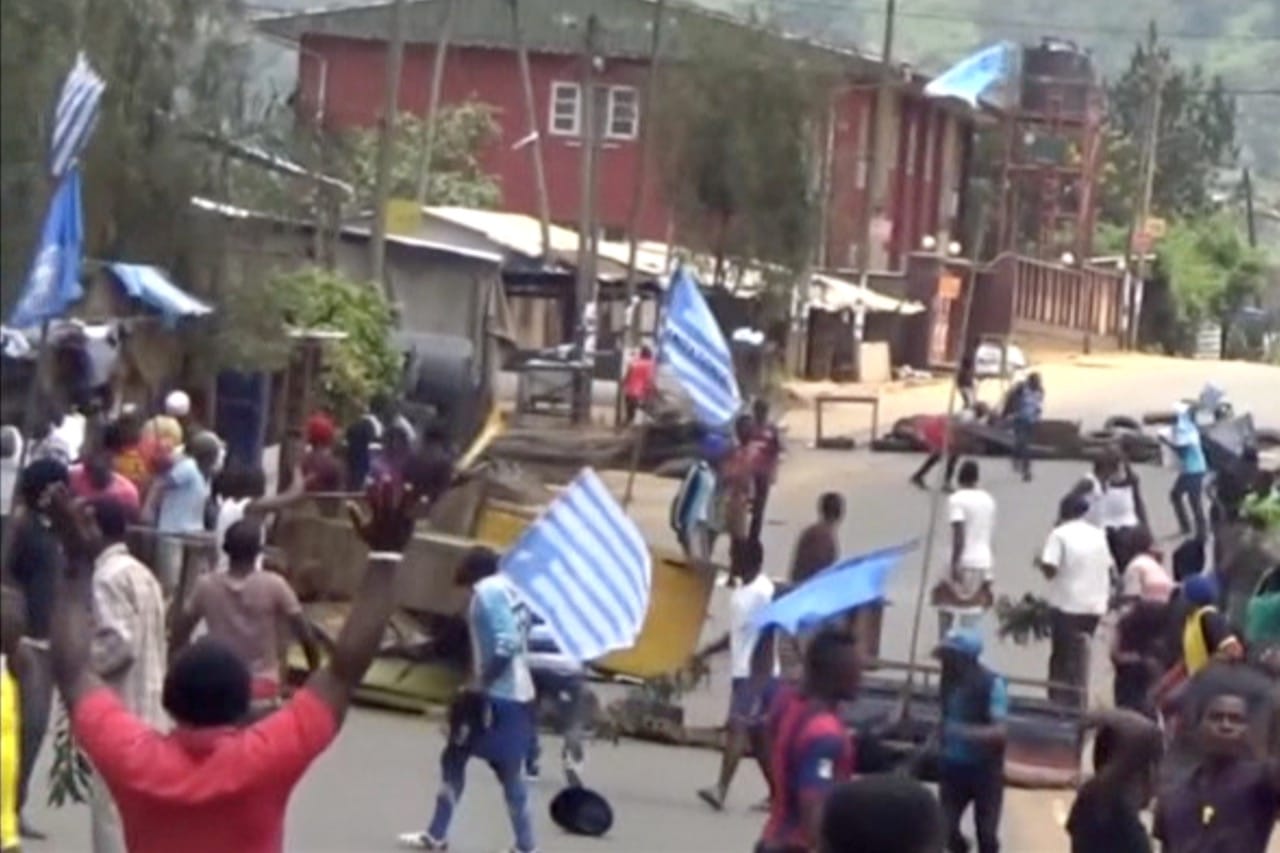 A still image taken from a video shot on 1 October 2017, shows protesters waving Ambazonian flags in front of a road block in the English-speaking city of Bamenda, Cameroon, REUTERS/via Reuters TV