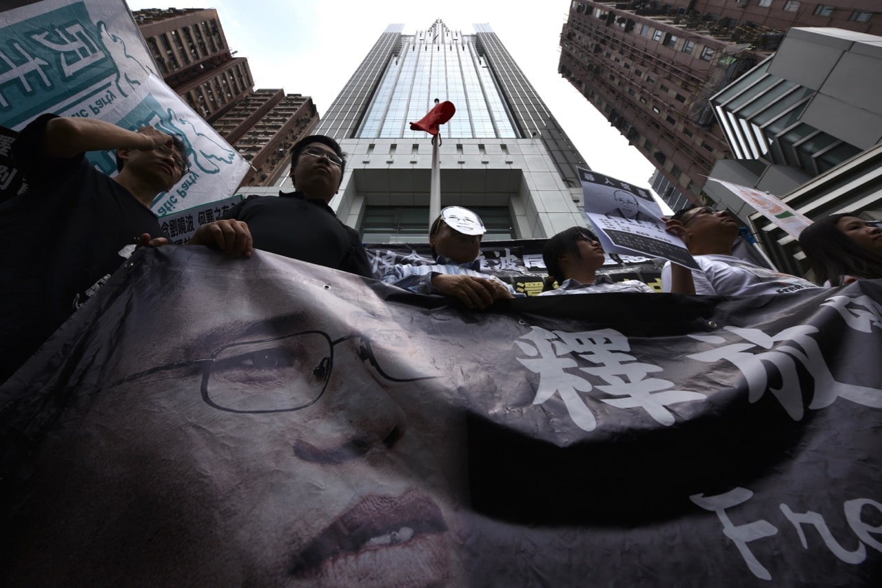 Veteran activist and former lawmaker Albert Ho (C) wears a mask depicting Liu Xia, wife of the late Chinese Nobel laureate Liu Xiaobo, during a protest in memory of Liu outside the Chinese Liaison Office in Hong Kong, 30 August 2017, ANTHONY WALLACE/AFP/Getty Images