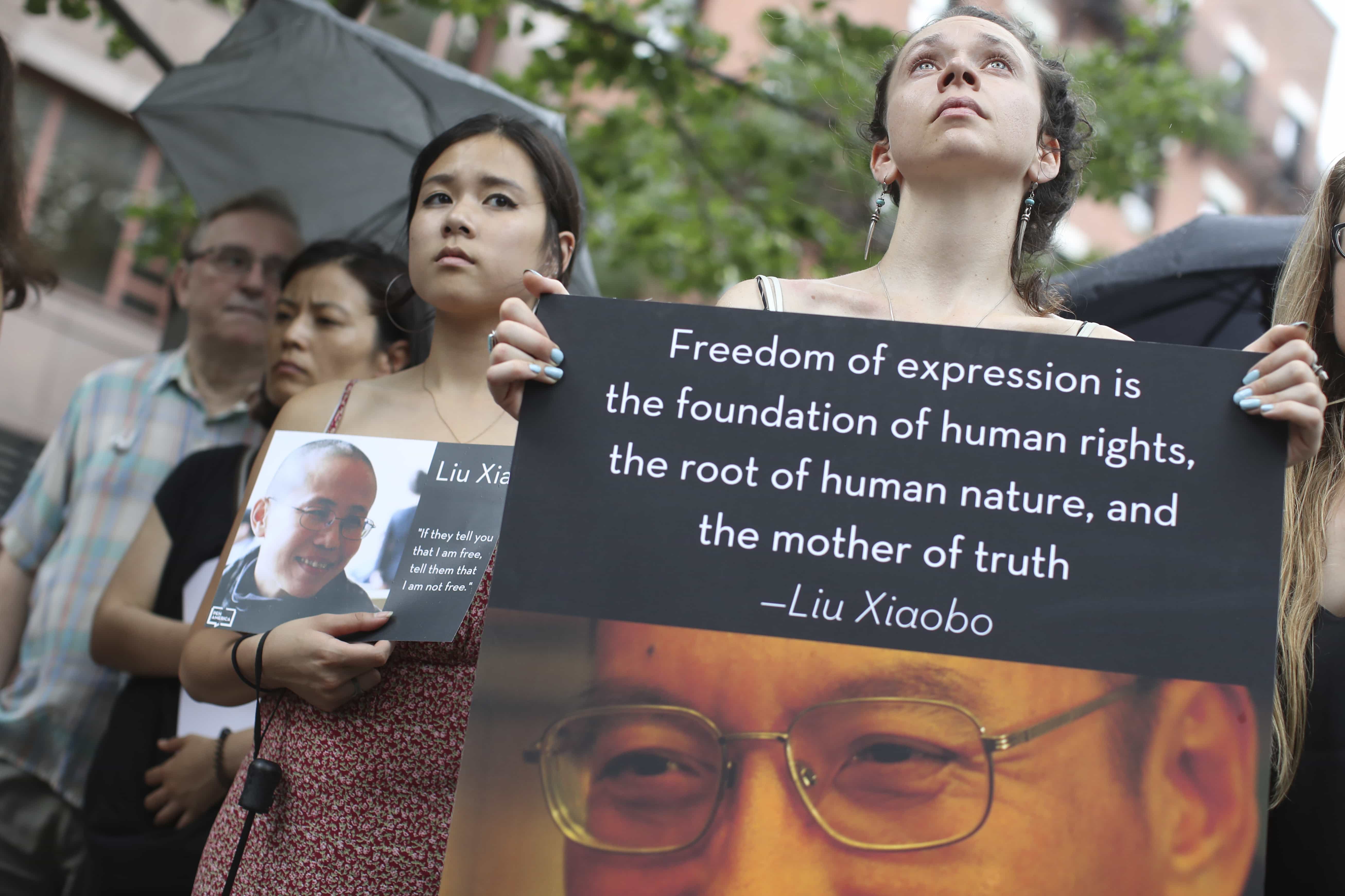 Participants hold photos of Liu Xiaobo, right, and his wife Liu Xia during a vigil honoring Liu Xiaobo's legacy and to protest continued human rights abuses in China, 13 July 2017, in New York, AP Photo/Mary Altaffer