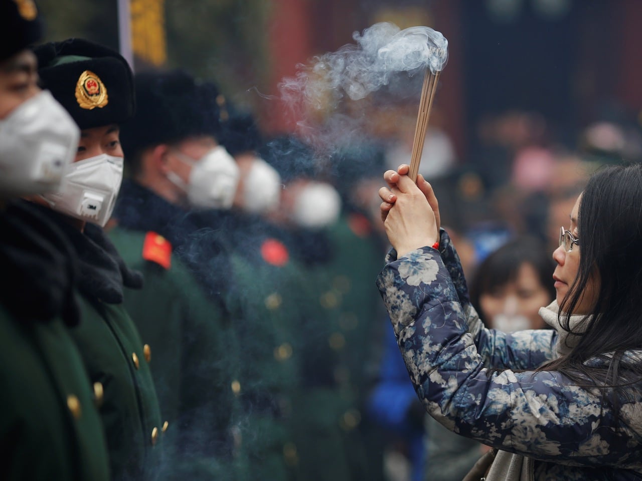 A woman prays in front of paramilitary policemen providing security as people gather at Yonghegong Lama Temple on the first day of the Lunar New Year in Beijing, 28 January 2017, REUTERS/Damir Sagolj