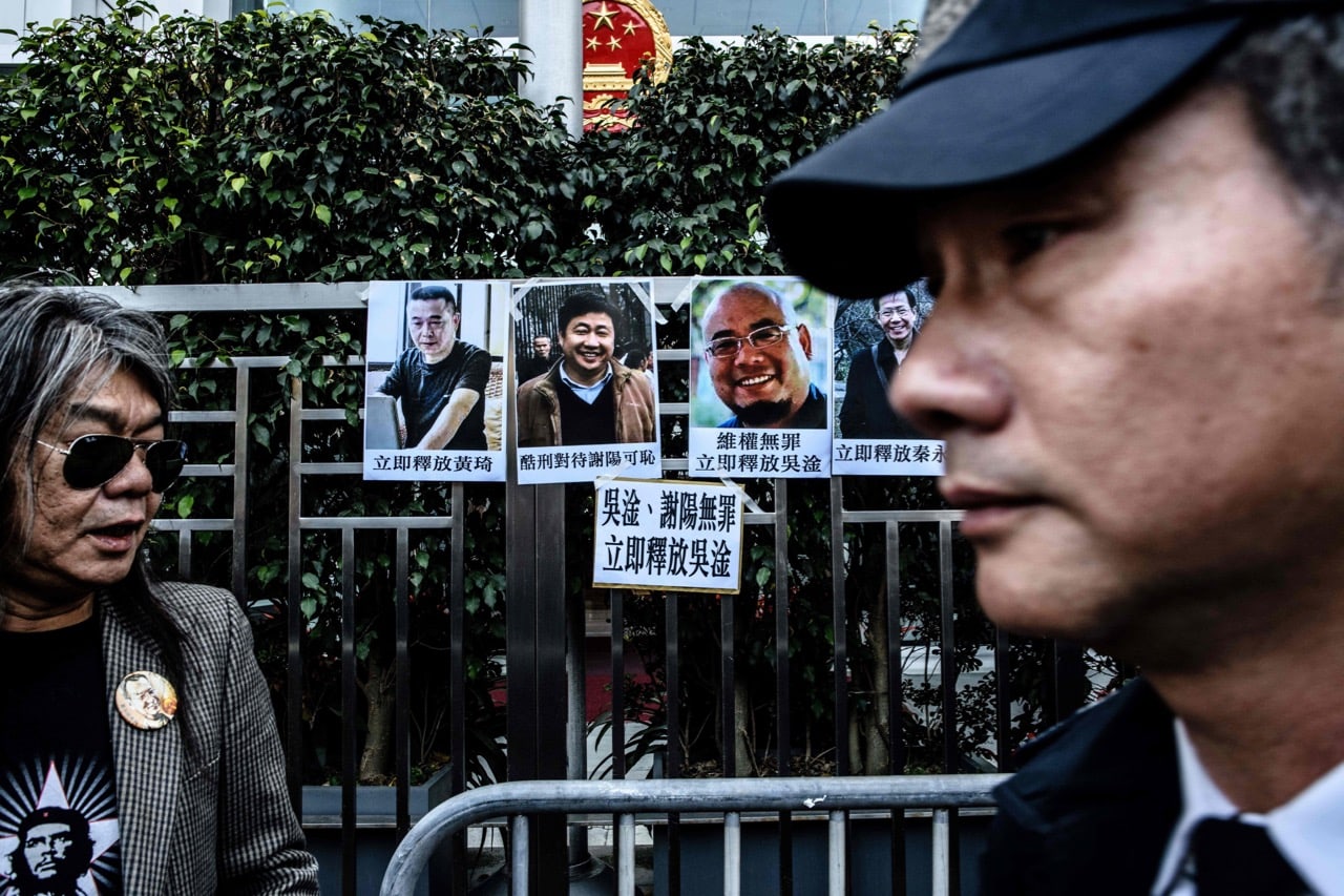 A former lawmaker stands next to posters of (back R to L) democracy activist Qin Yongmin and three other dissidents during a protest outside the Chinese Liaison Office in Hong Kong, 27 December 2017, ANTHONY WALLACE/AFP/Getty Images