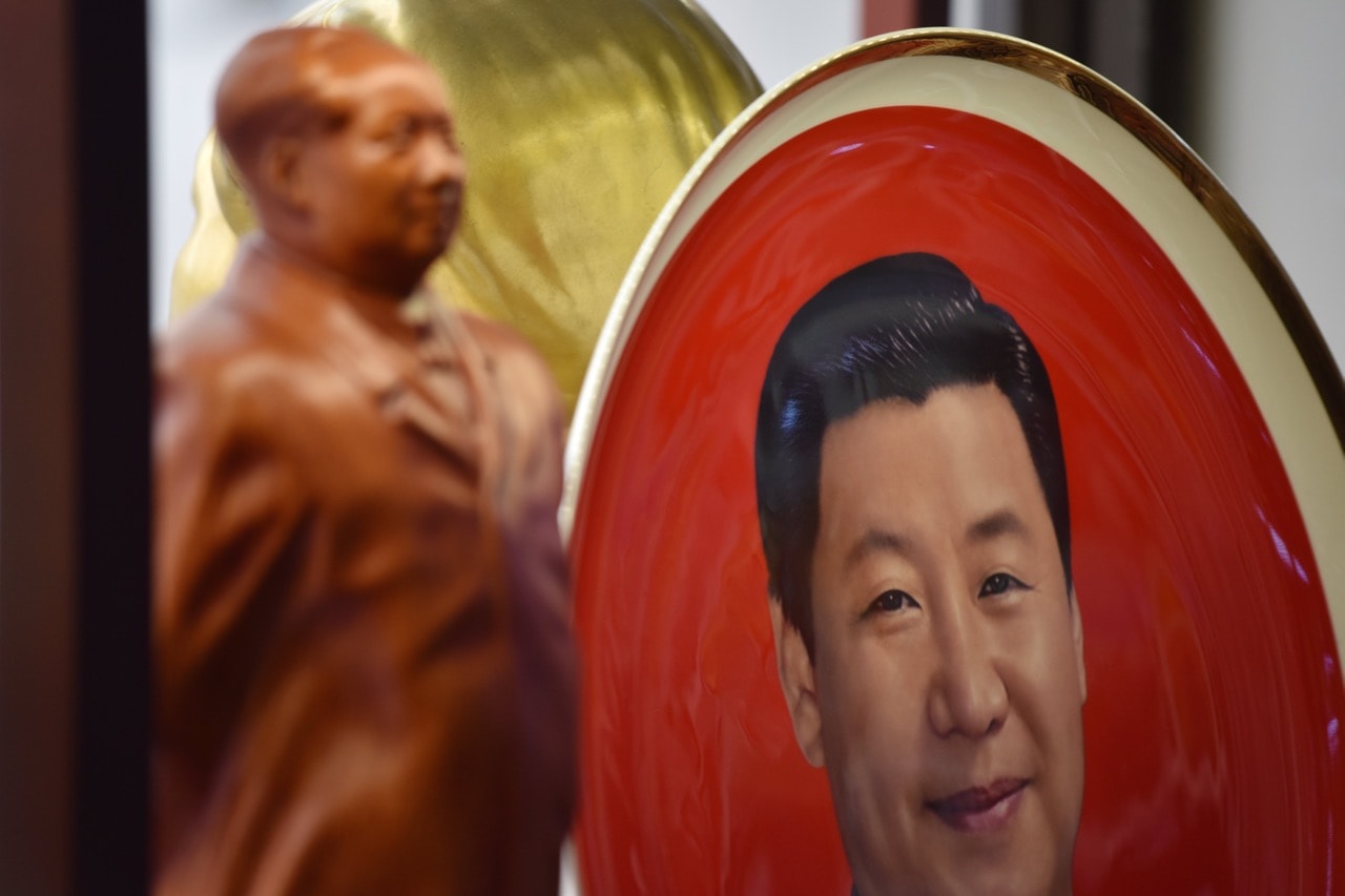 A decorative plate featuring an image of President Xi Jinping is seen behind a statue of late communist leader Mao Zedong at a souvenir store in Beijing, China, 27 February 2018, GREG BAKER/AFP/Getty Images