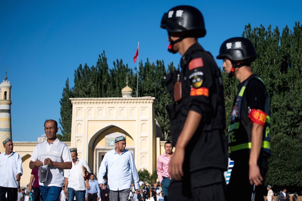 Police officers patrol the area as Muslims leave the Id Kah Mosque after the morning prayer in the town of Kashgar, in China's Xinjiang Uighur Autonomous Region, 26 June 2017, JOHANNES EISELE/AFP/Getty Images