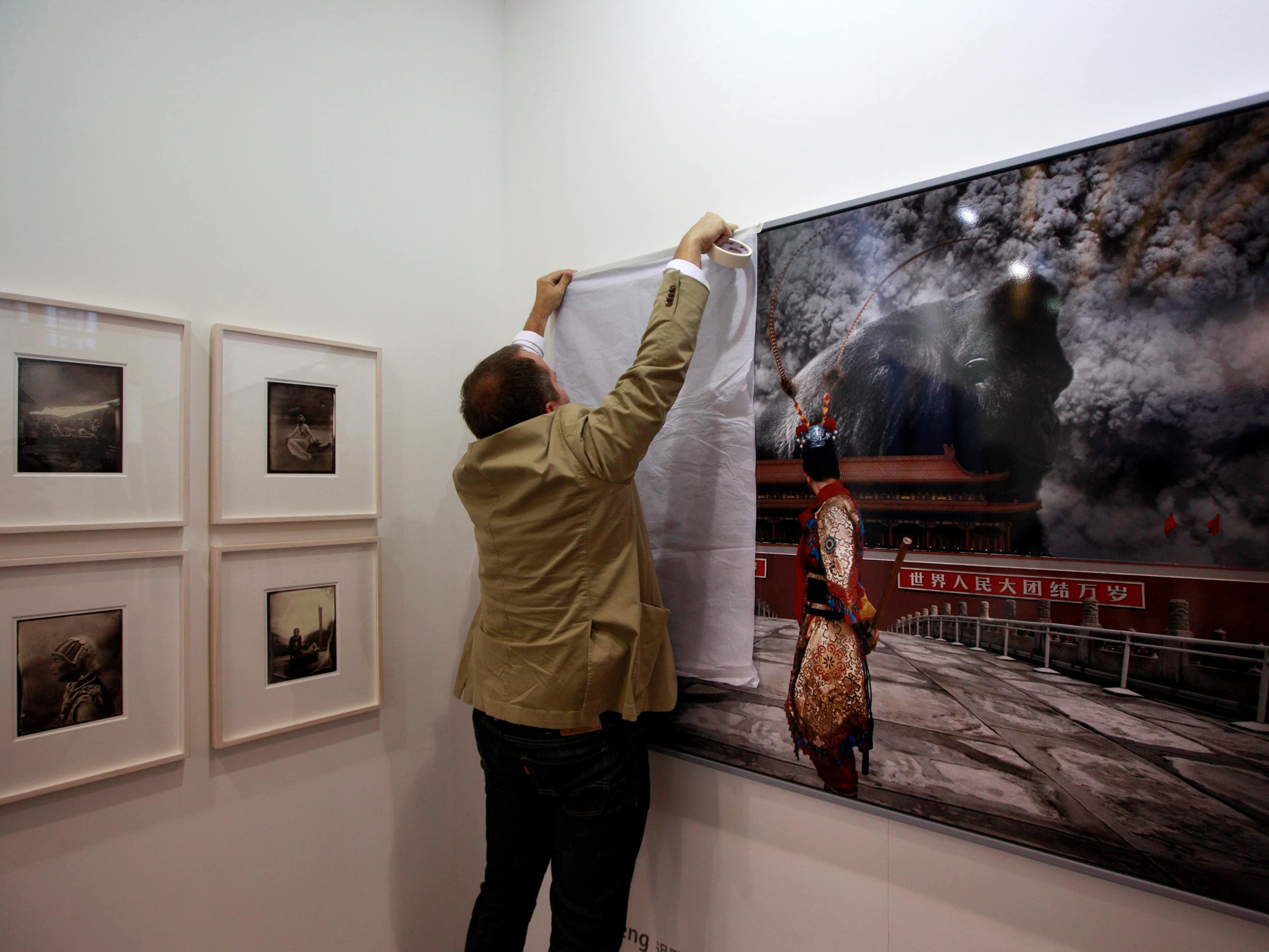 A member of an art gallery covers a piece by artist Chi Peng after government officials deemed it unfit for display before the SH Contemporary Art Fair in Shanghai, 6 September 2012, REUTERS/Stringer