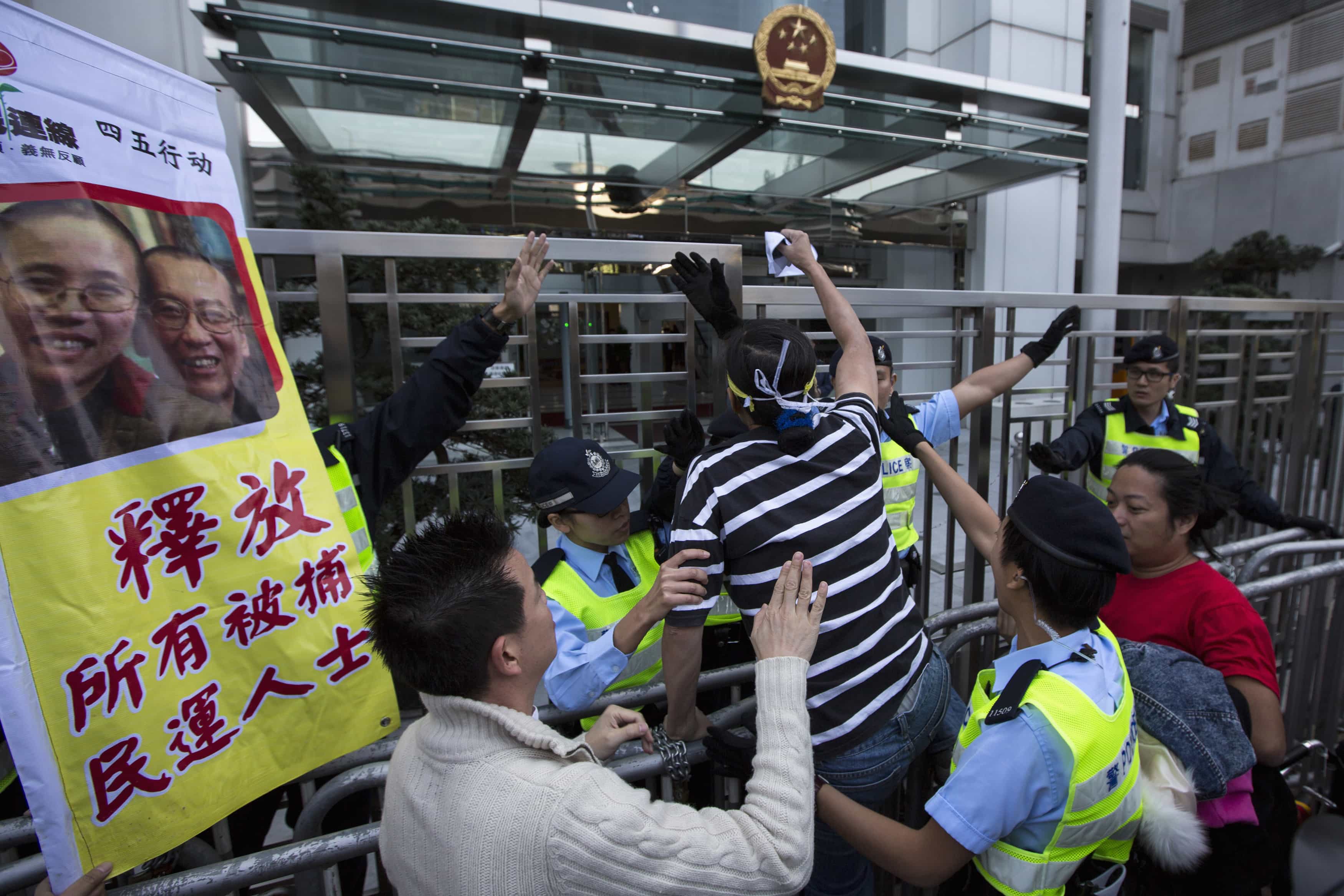 A pro-democracy activist attempts to climb a barrier during a protest to urge for the release of Liu Xiaobo and his wife Liu Xia outside the Chinese liaison office in Hong Kong, 5 December 2013, REUTERS/Tyrone Siu