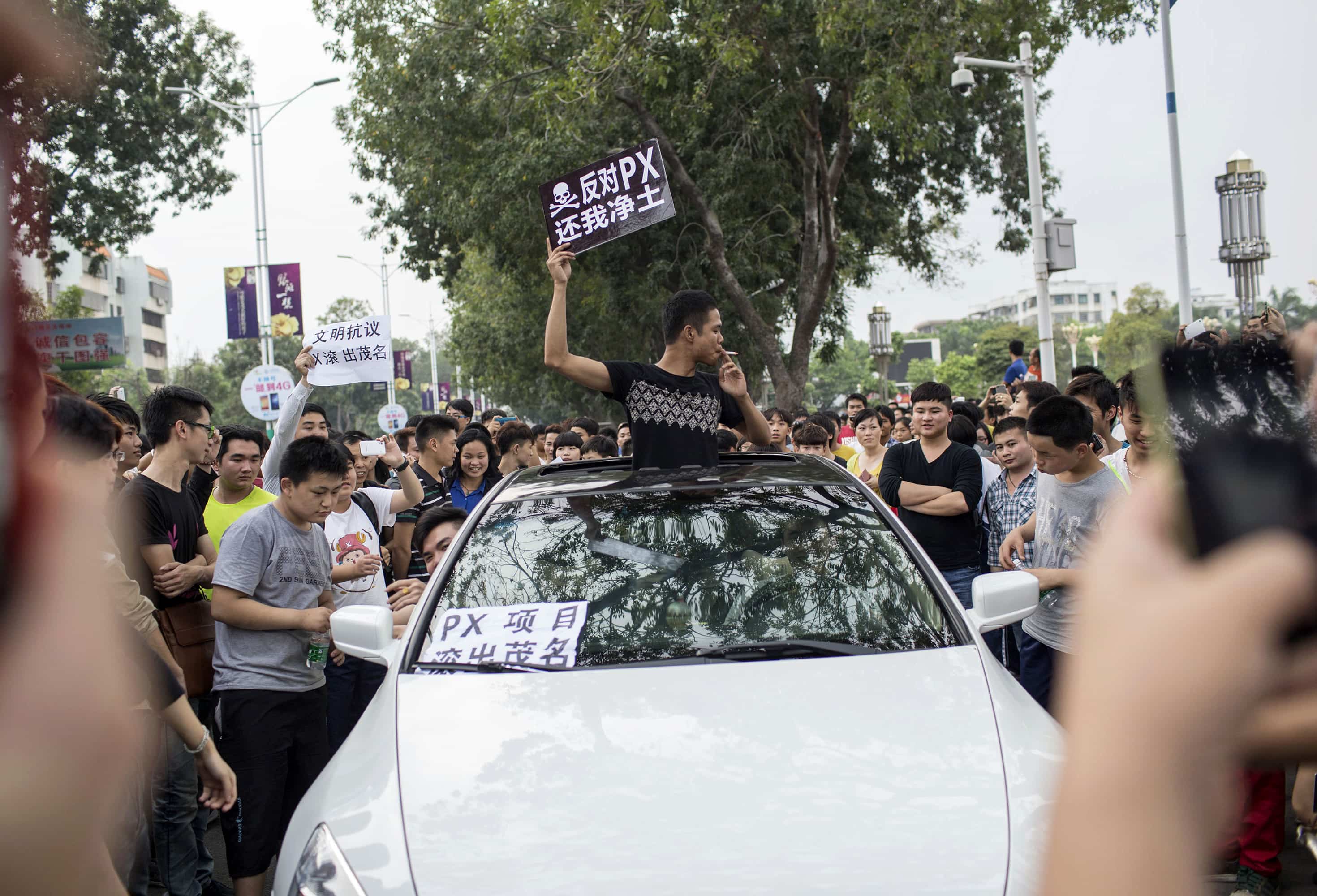 A man (C) raises a placard which reads, "Oppose PX (paraxylene petrochemicals), give me back my pure land", as he and other residents protest against a chemical plant project in Maoming, Guangdong province, 31 March 2014, REUTERS/Stringer