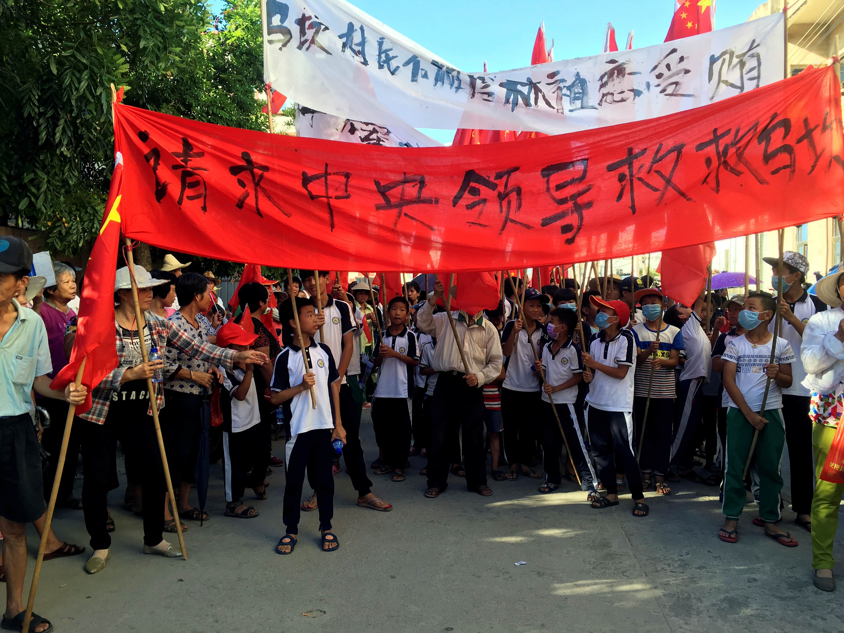 Villagers carry banners which read "Plead the central government to help Wukan" (in red) villagers don't believe Lin Zuluan took bribes" during a protest in Wukan, China's Guangdong province, 22 June 2016, REUTERS/James Pomfret