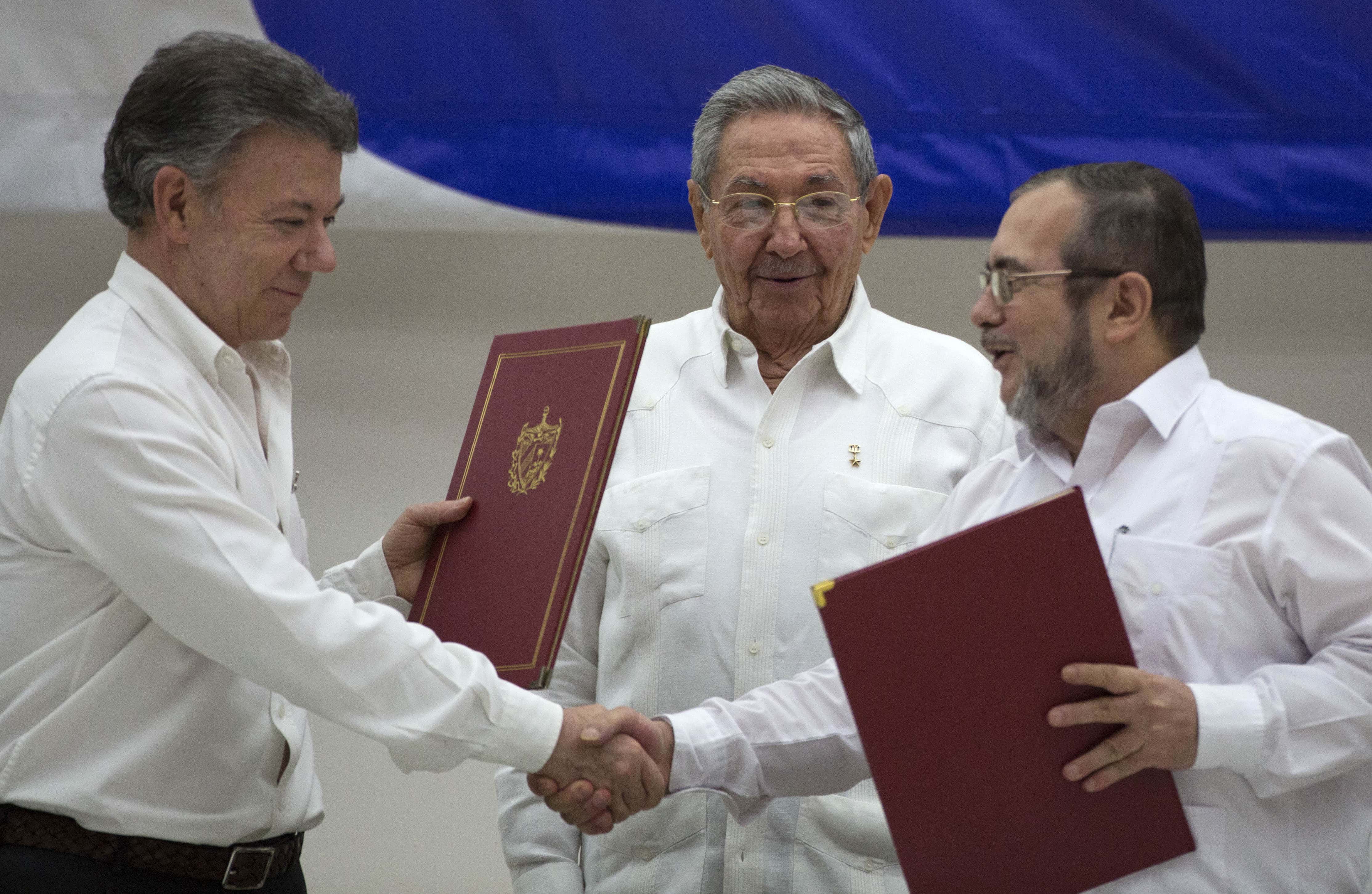 Commander of the FARC, Rodrigo Londono, right, shakes the hand of Colombian President Juan Manuel Santos, left, during a signing ceremony of a cease-fire deal, in Havana, Cuba, 23 June 2016, AP Photo/Desmond Boylan