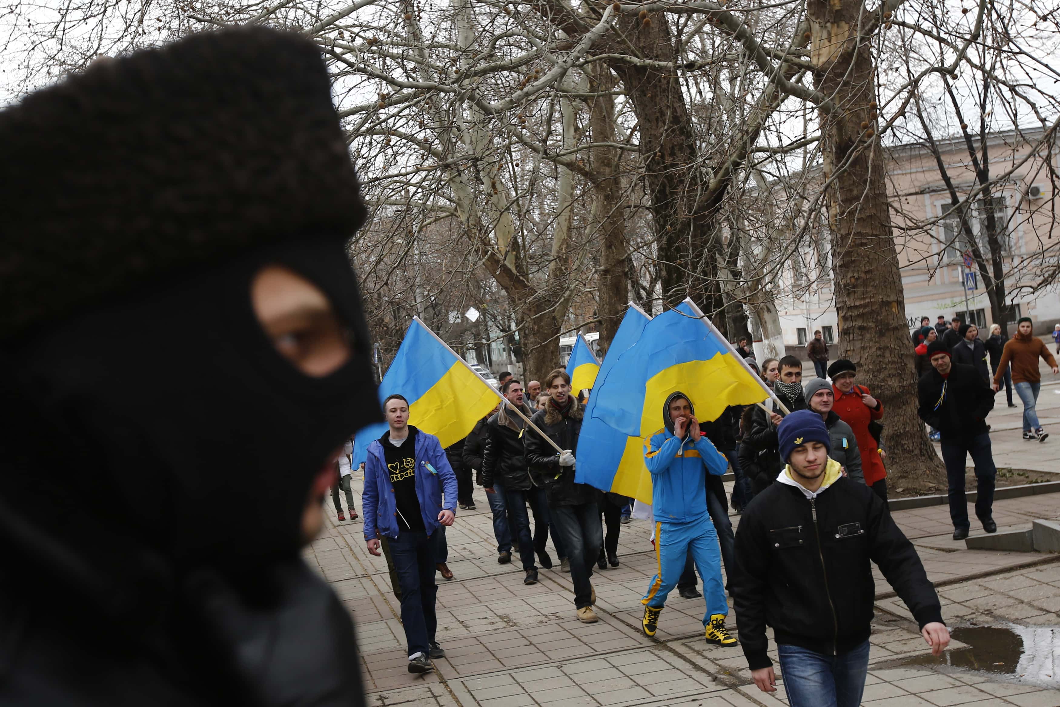 A member of a pro-Russian self-defense unit (L) watches pro-Ukraine protesters march near the local parliament building in the Crimean city of Simferopol, 8 March 2014. , REUTERS/Thomas Peter