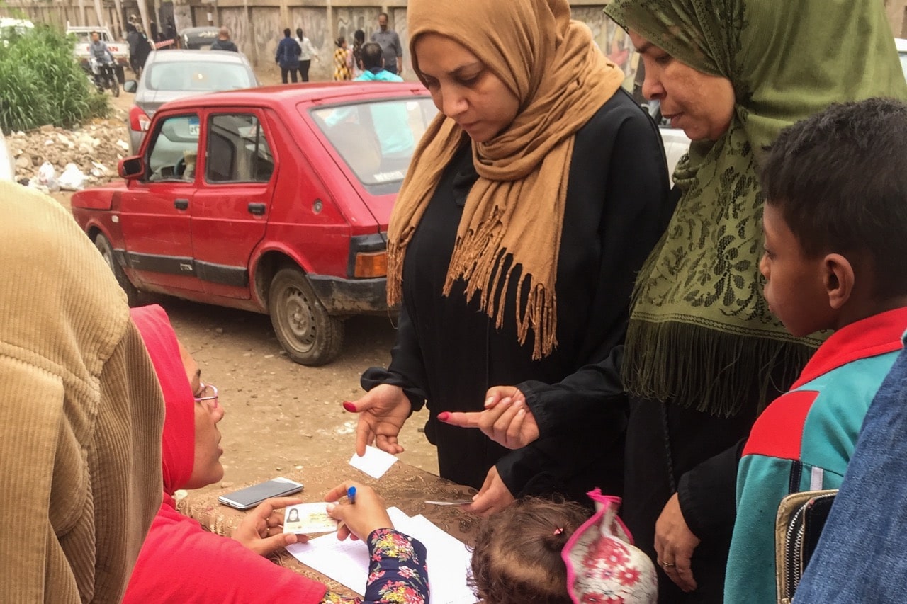 An employee checks for phosphorous ink on a resident's finger during the distribution of staple commodities as part of an effort to mobilize voters during the 2018 presidential election, in Giza, Egypt, 28 March 2018, Islam Safwat/NurPhoto via Getty Images