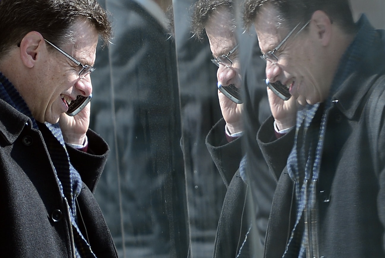 A man is reflected in paneling as he speaks on his phone at the Mobile World Congress, 26 February 2013, in Barcelona, Spain., AP Photo/Manu Fernandez, File